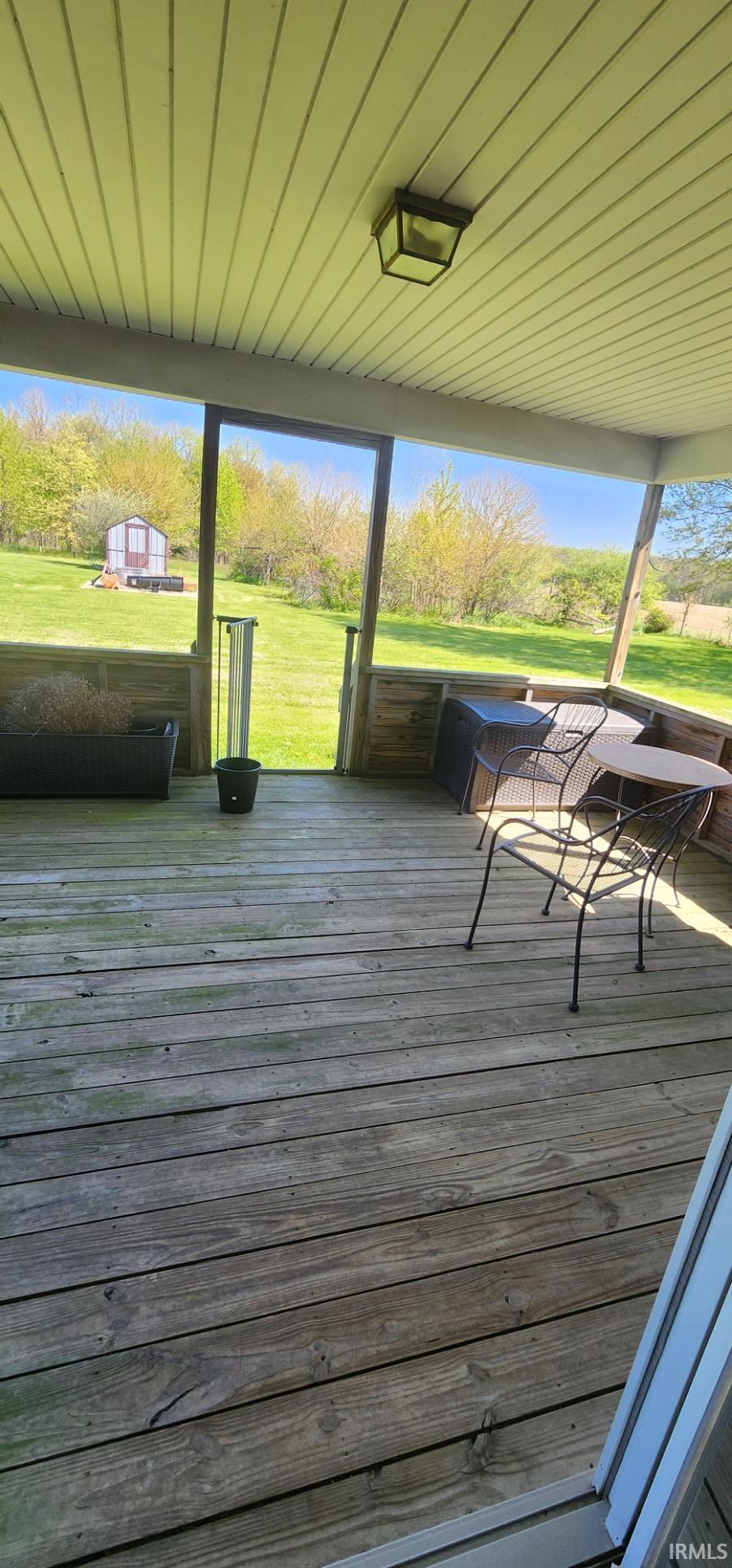 Expansive covered porch featuring wood-finish decking, a paneled ceiling, and an overhead lighting fixture