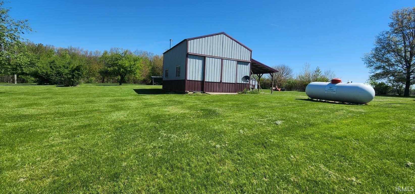 Metal-sided structure with a covered porch and expansive grassy grounds