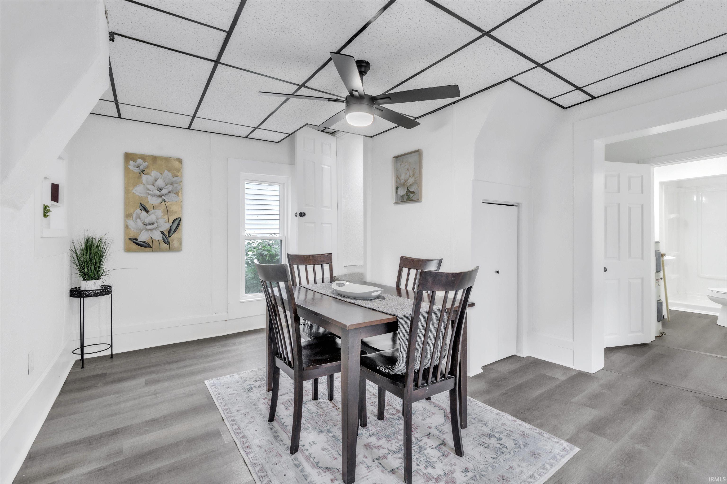 Modern dining area featuring wood-finish flooring, a ceiling fan, and white walls with decorative trim