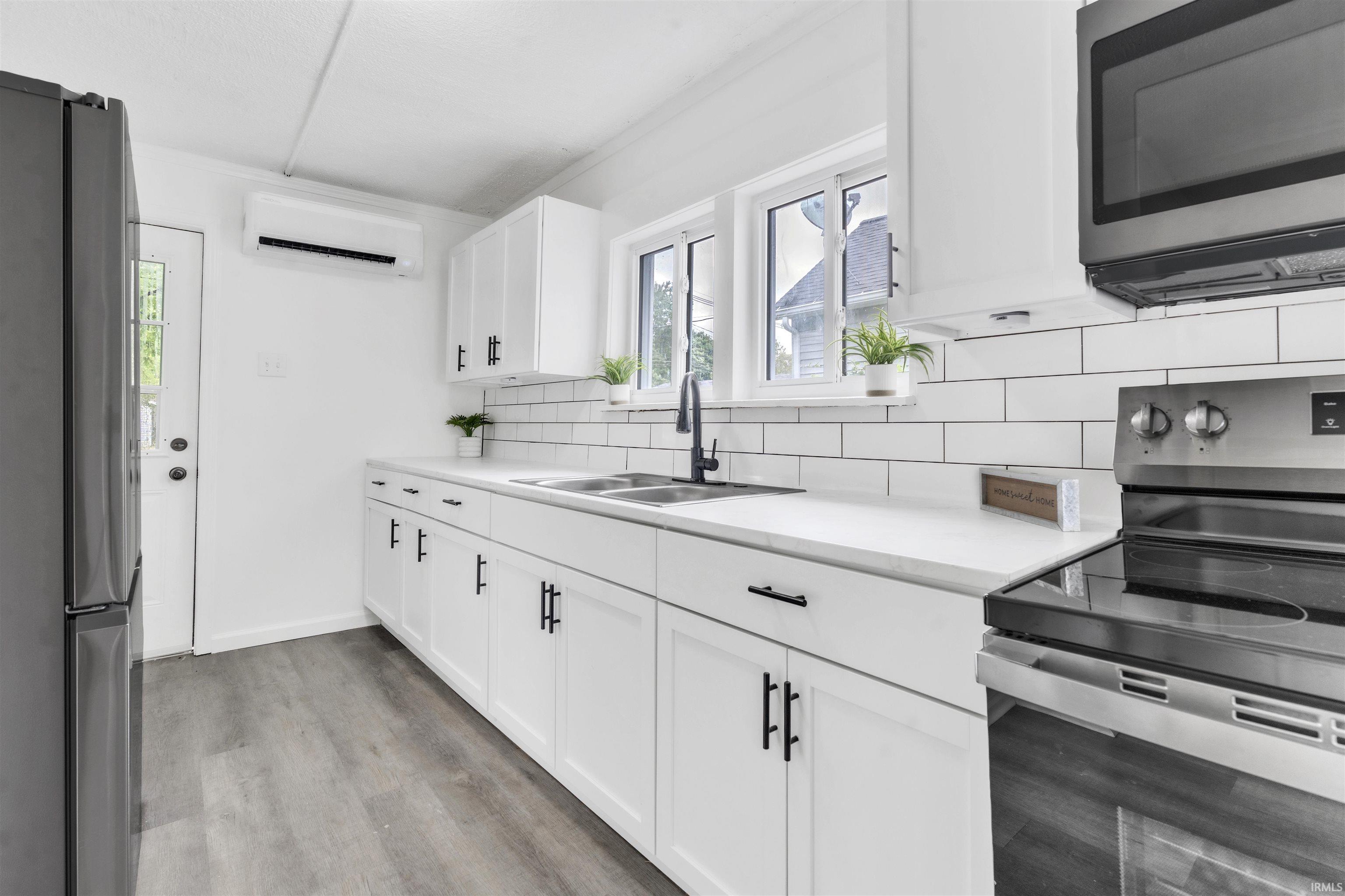 Kitchen featuring white shaker-style cabinetry, matte black hardware, white subway tile backsplash, white countertops, and wood-finish flooring