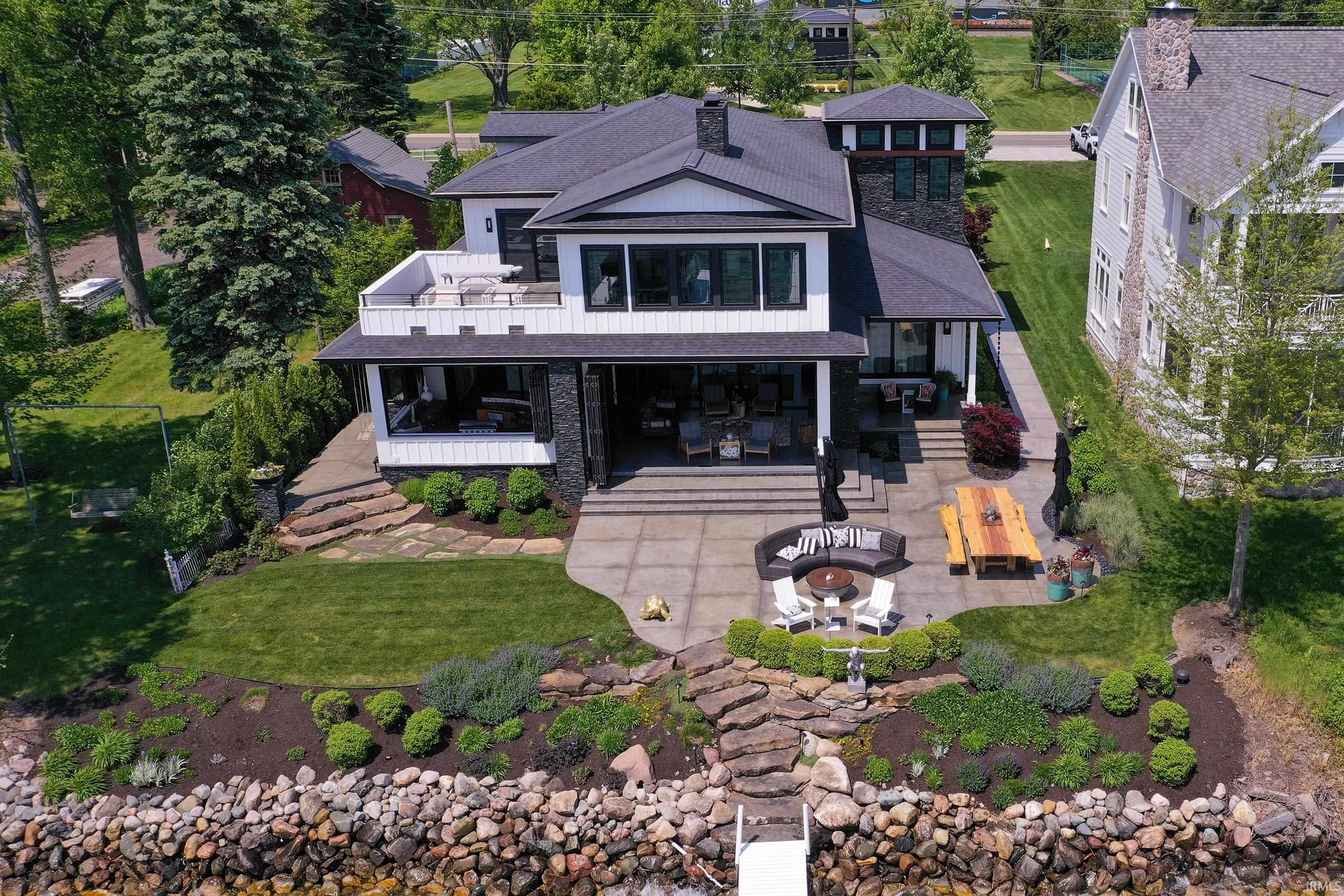 Modern waterfront residence featuring a multi-level outdoor living space, large upper-level balcony, and expansive lower-level patio