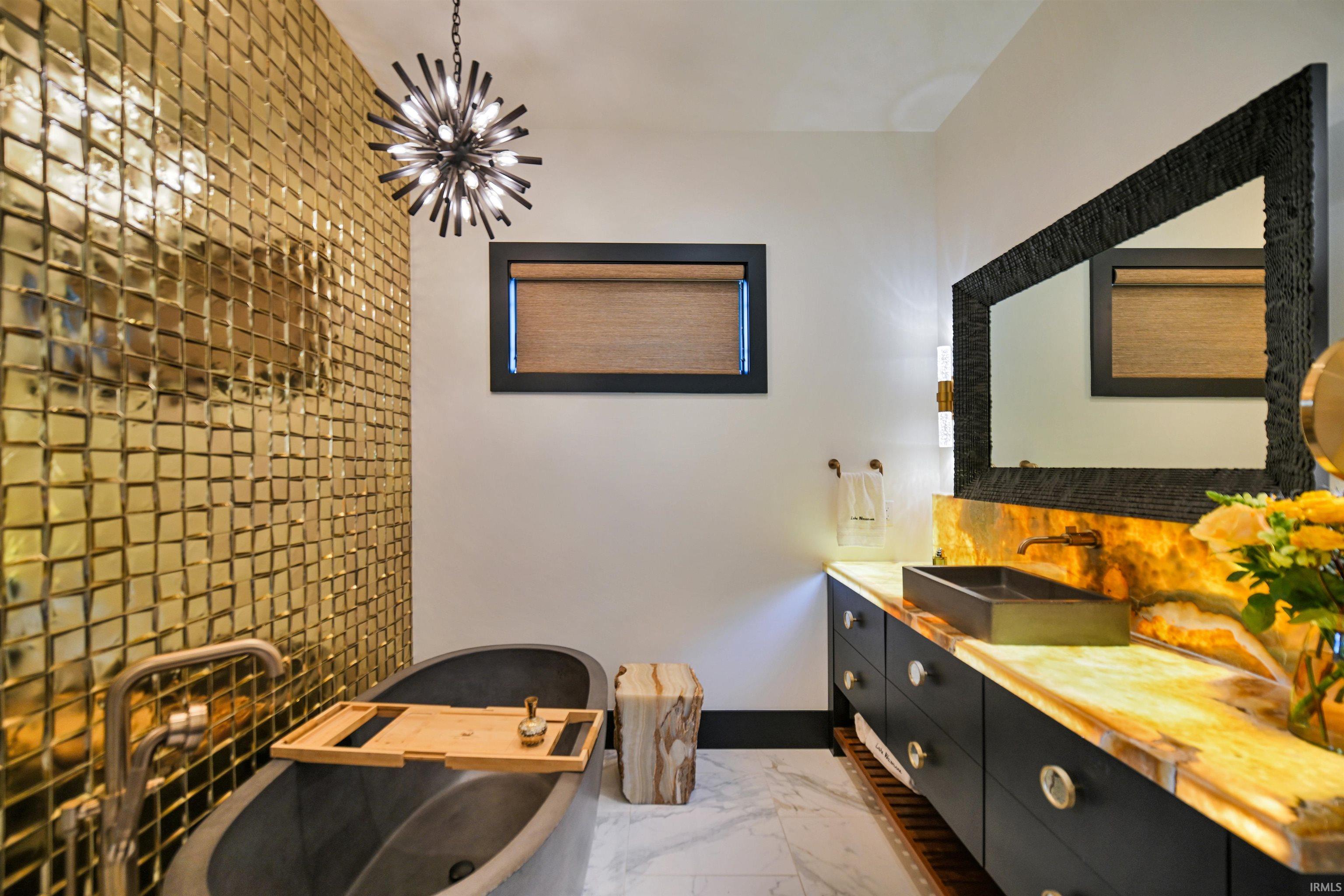 Bathroom featuring a textured gold tile accent wall and a freestanding soaking tub