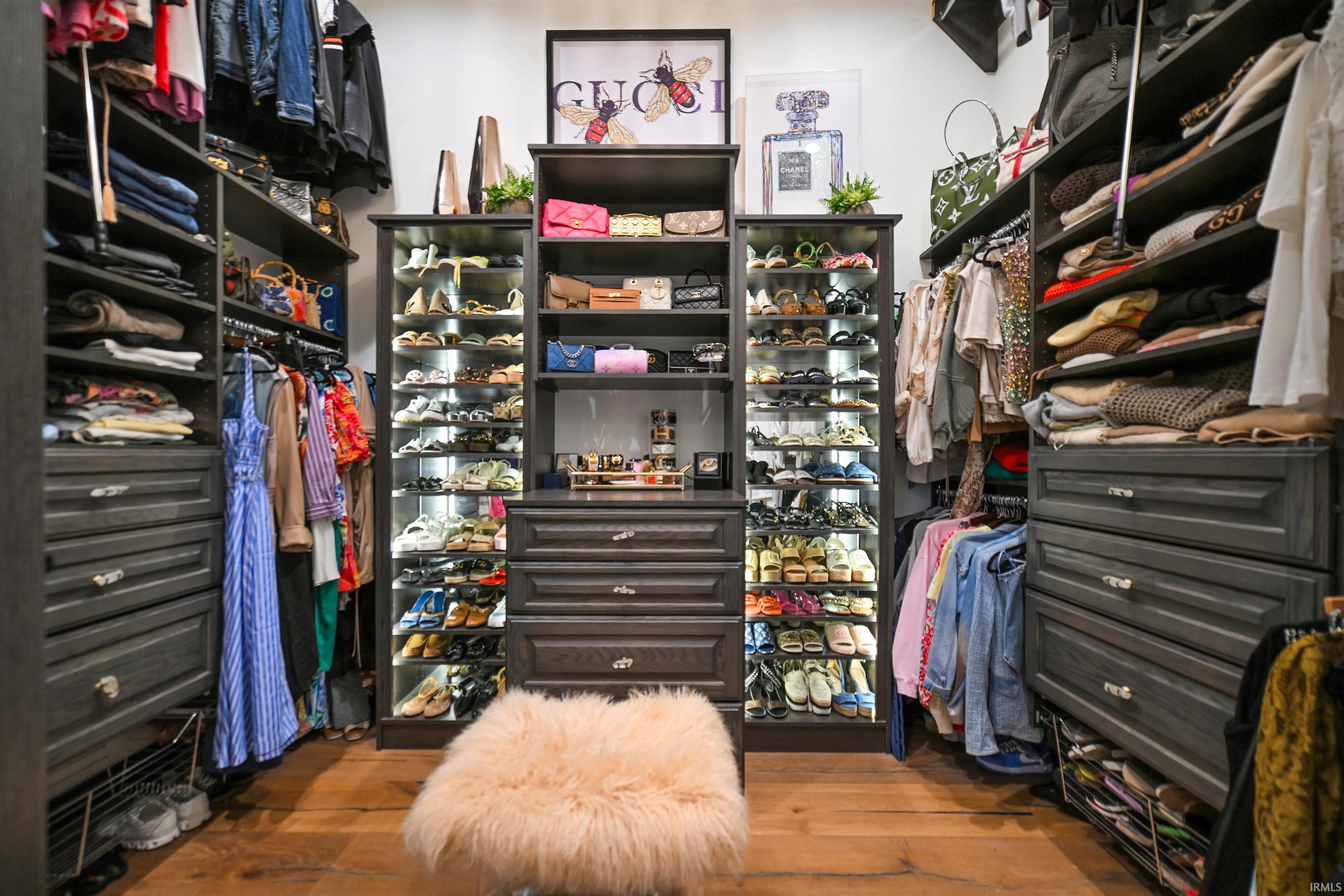 Custom closet system featuring dark wood-finish cabinetry, integrated shelving, hanging rods, display cases with interior lighting, and multiple drawer units