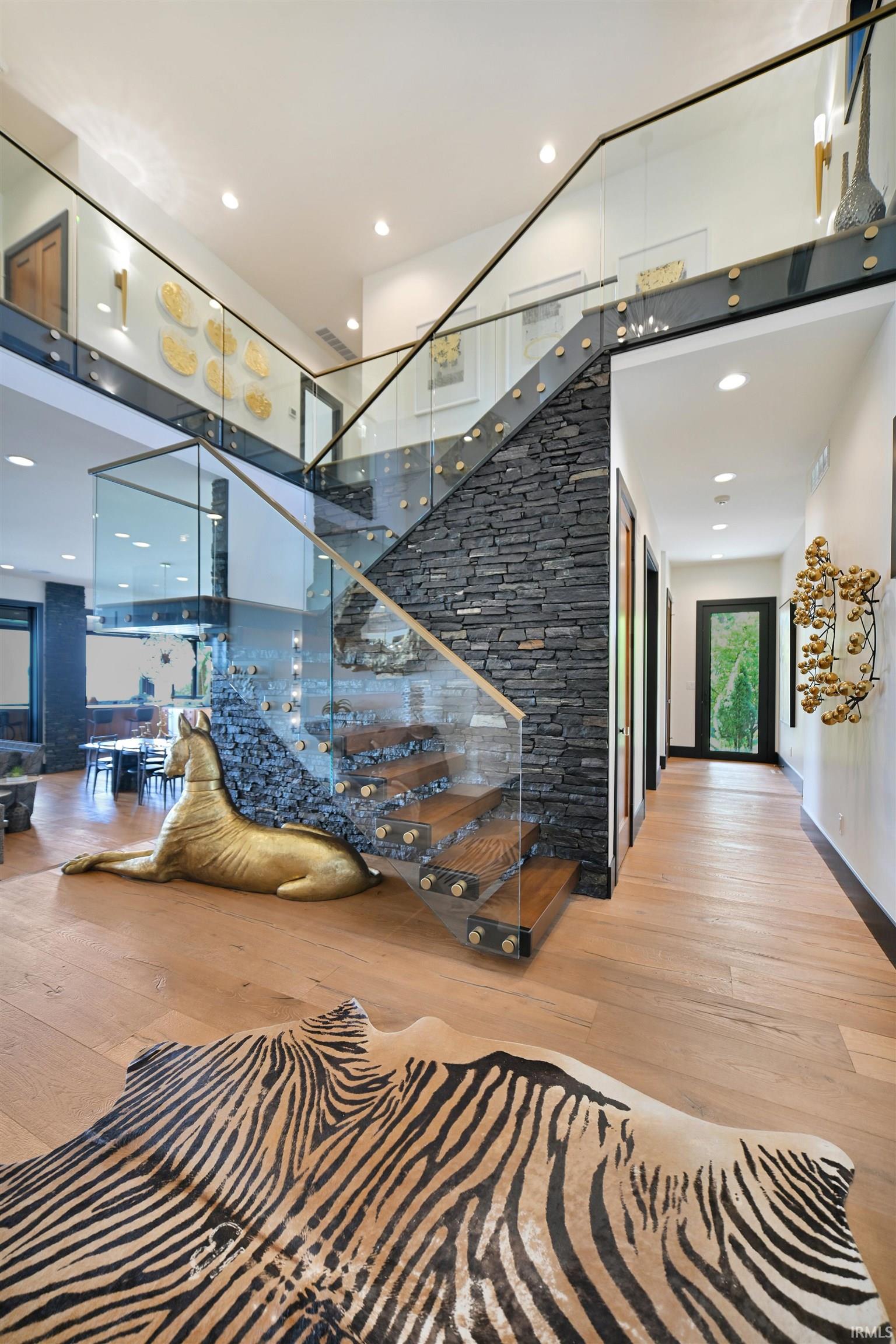 Grand entryway featuring a floating wood staircase with a glass and metal railing system