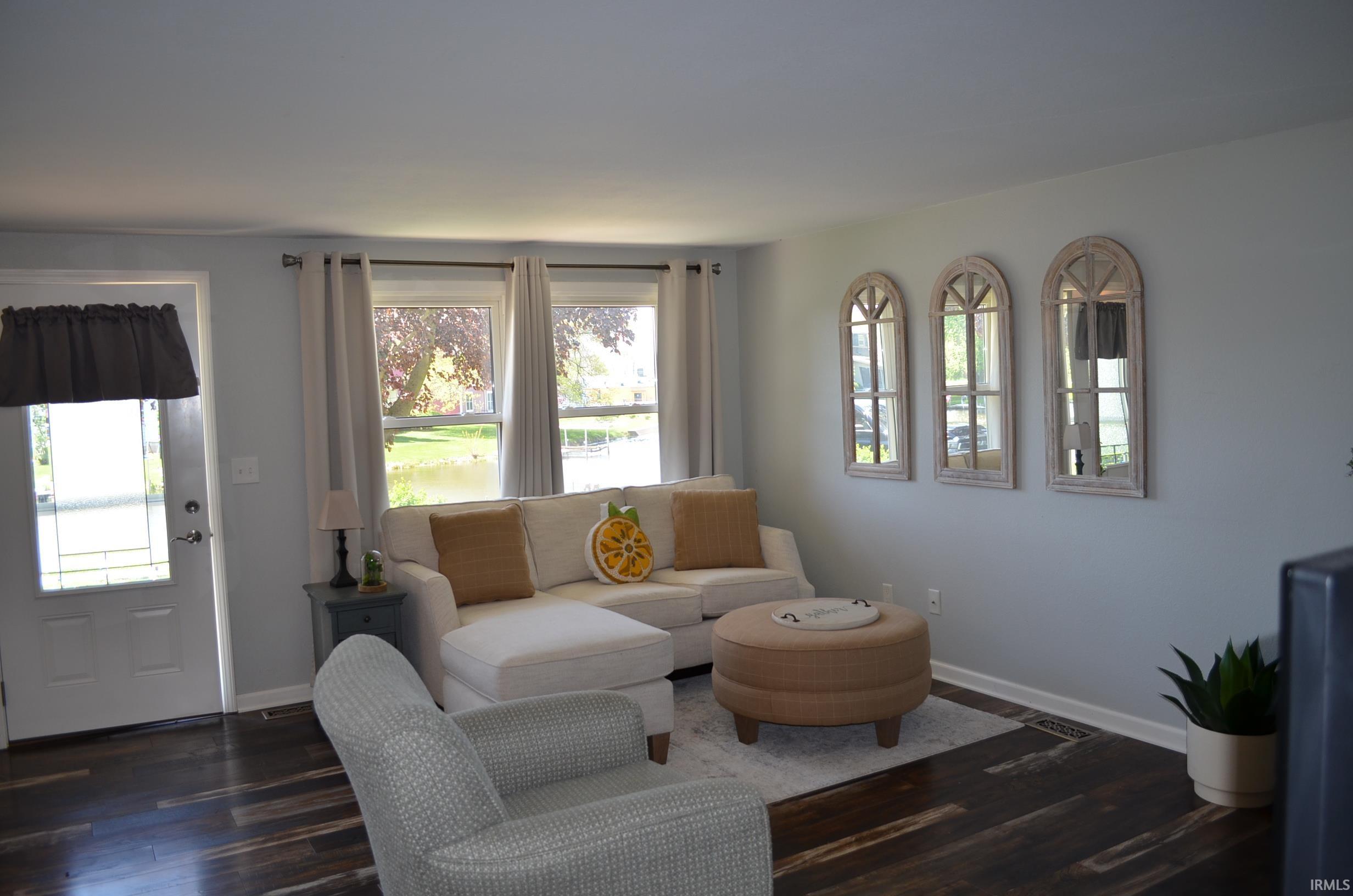 Bright living area featuring wood-finish flooring, light gray wall paint, and multiple windows