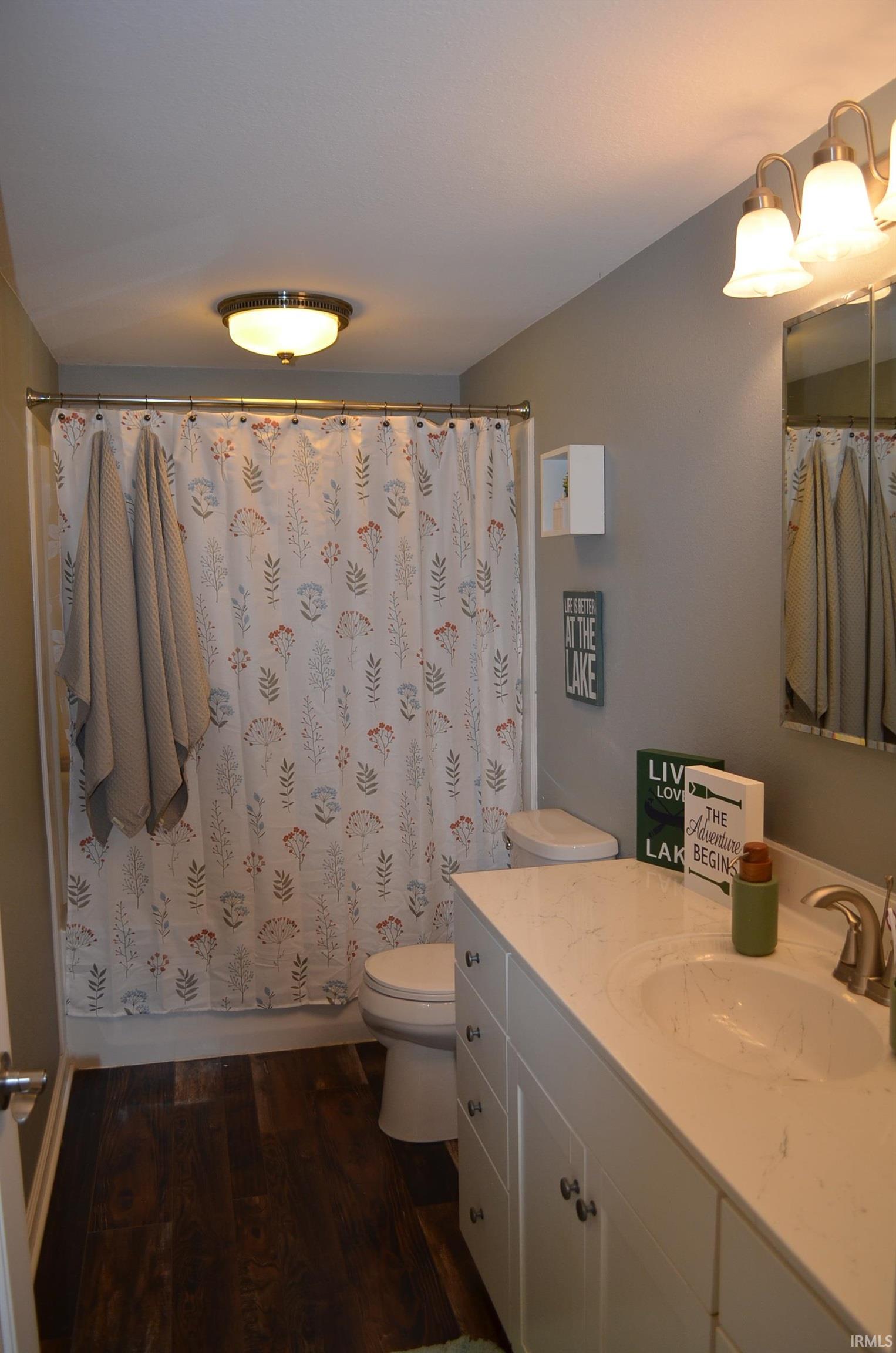Full bathroom featuring a white vanity with an integrated sink, a brushed nickel faucet, and a wall-mounted mirror with overhead lighting