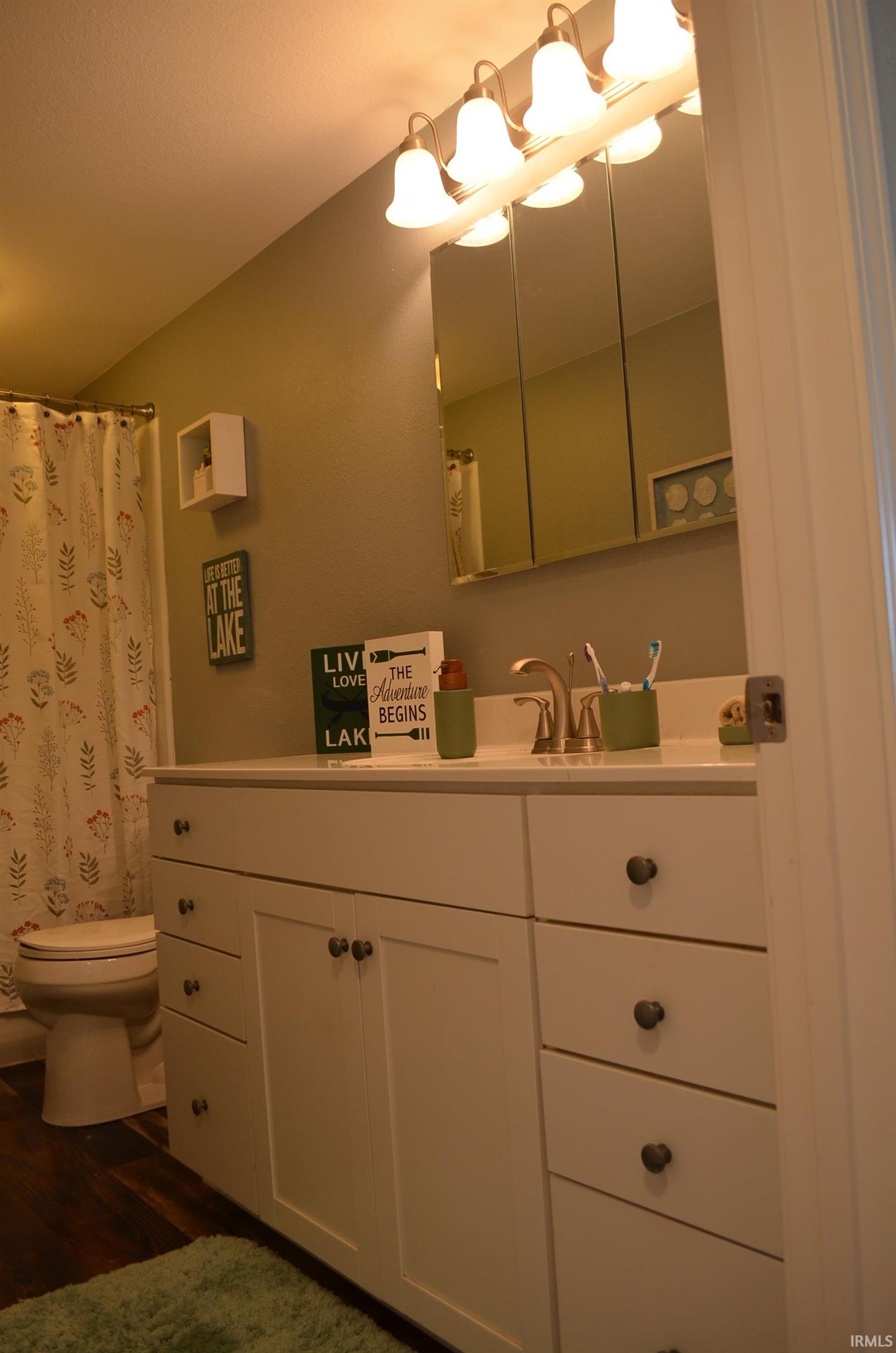 Bathroom featuring a white vanity with multiple drawers and cabinet storage, a white countertop, and a brushed nickel faucet