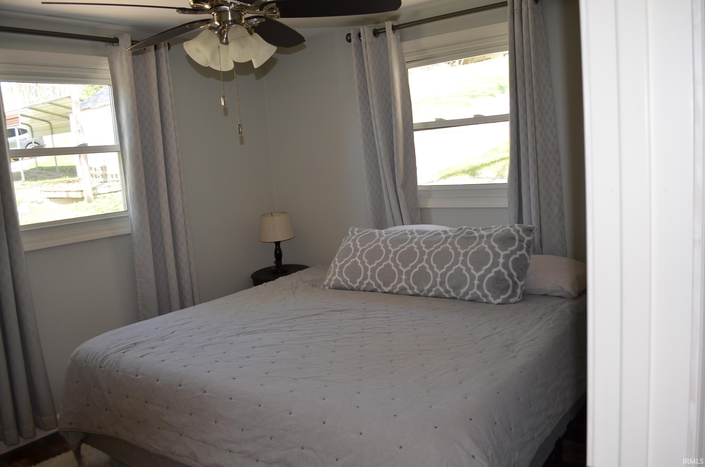 Room featuring two casement windows with white trim, light gray walls, and a ceiling fan with integrated lighting