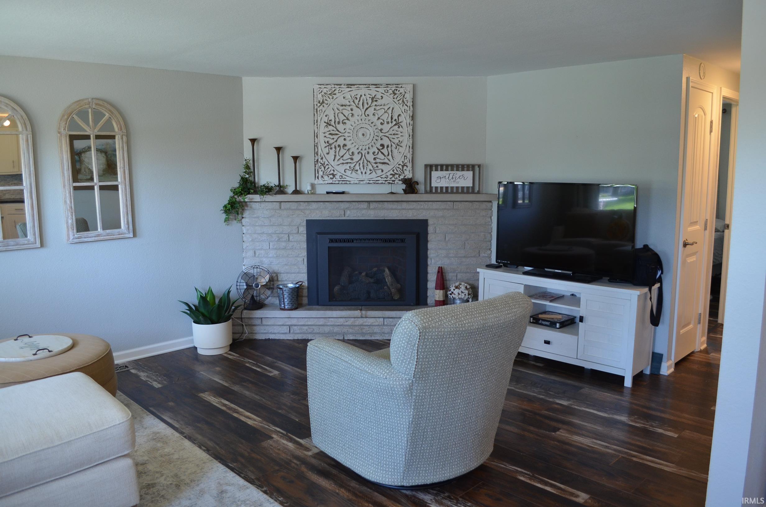 Living area featuring a stone-clad corner fireplace with a black insert