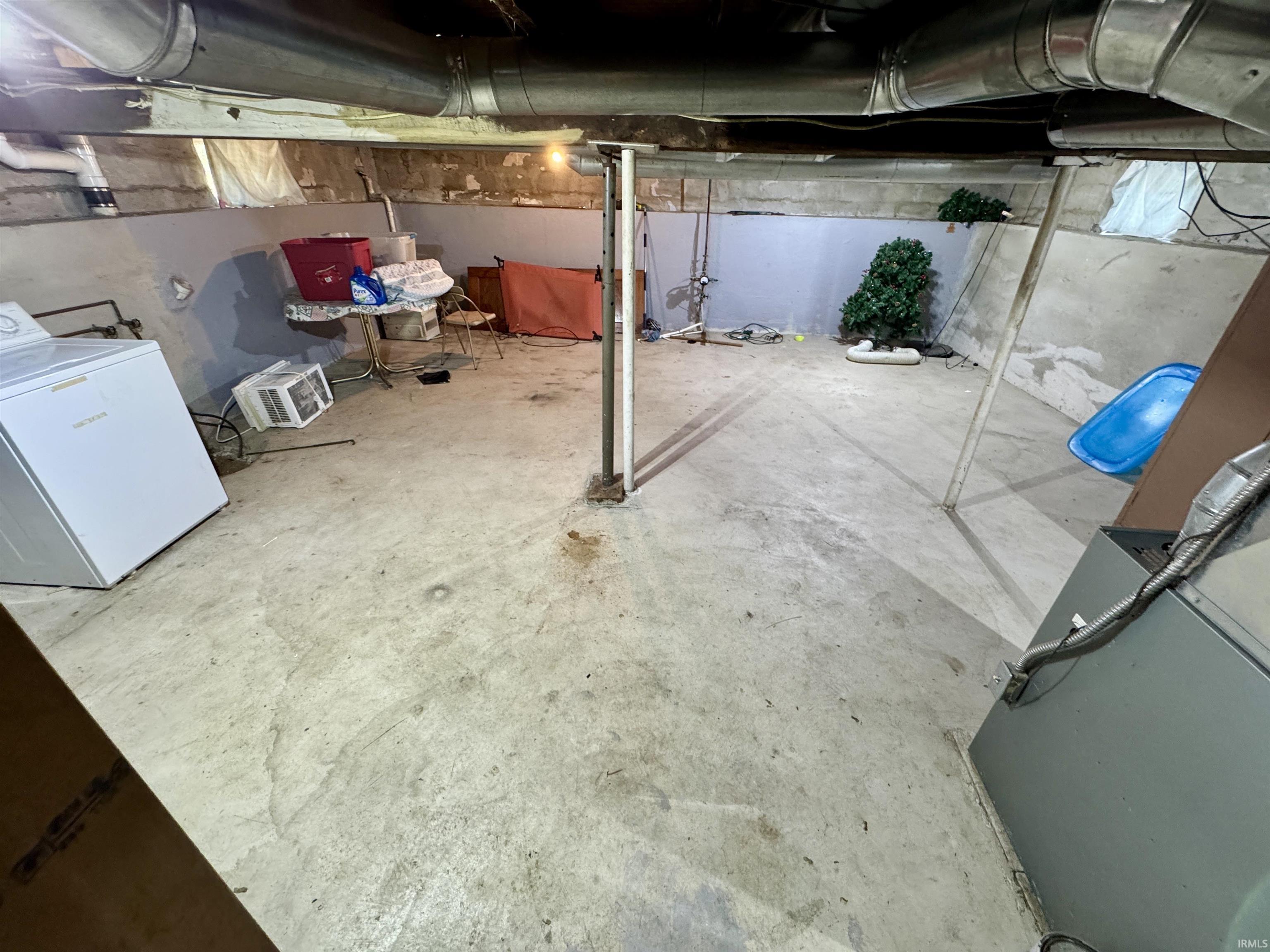 Unfinished basement featuring exposed ductwork, concrete flooring, and foundation walls