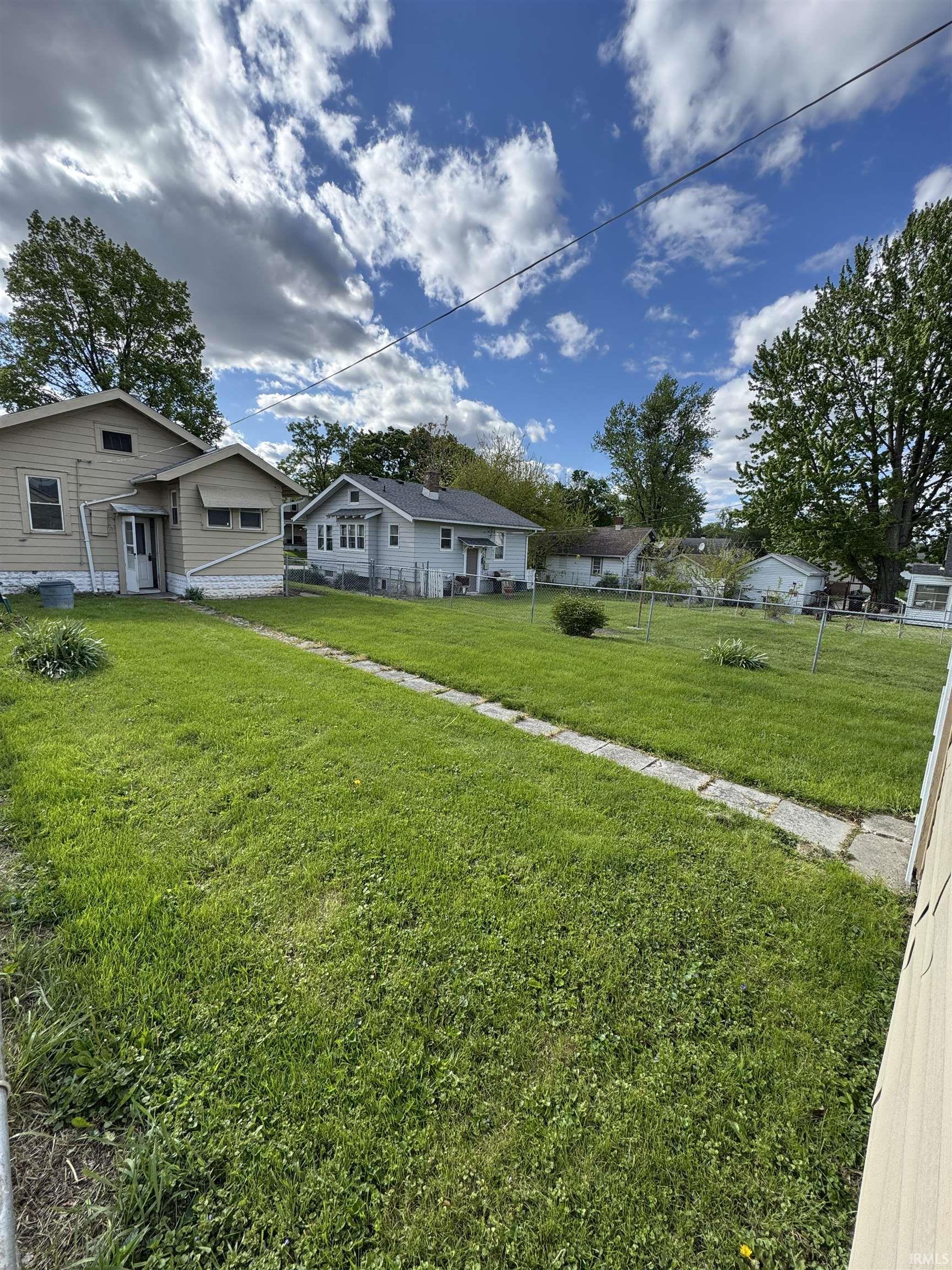Expansive grassy yard with a concrete pathway and mature trees