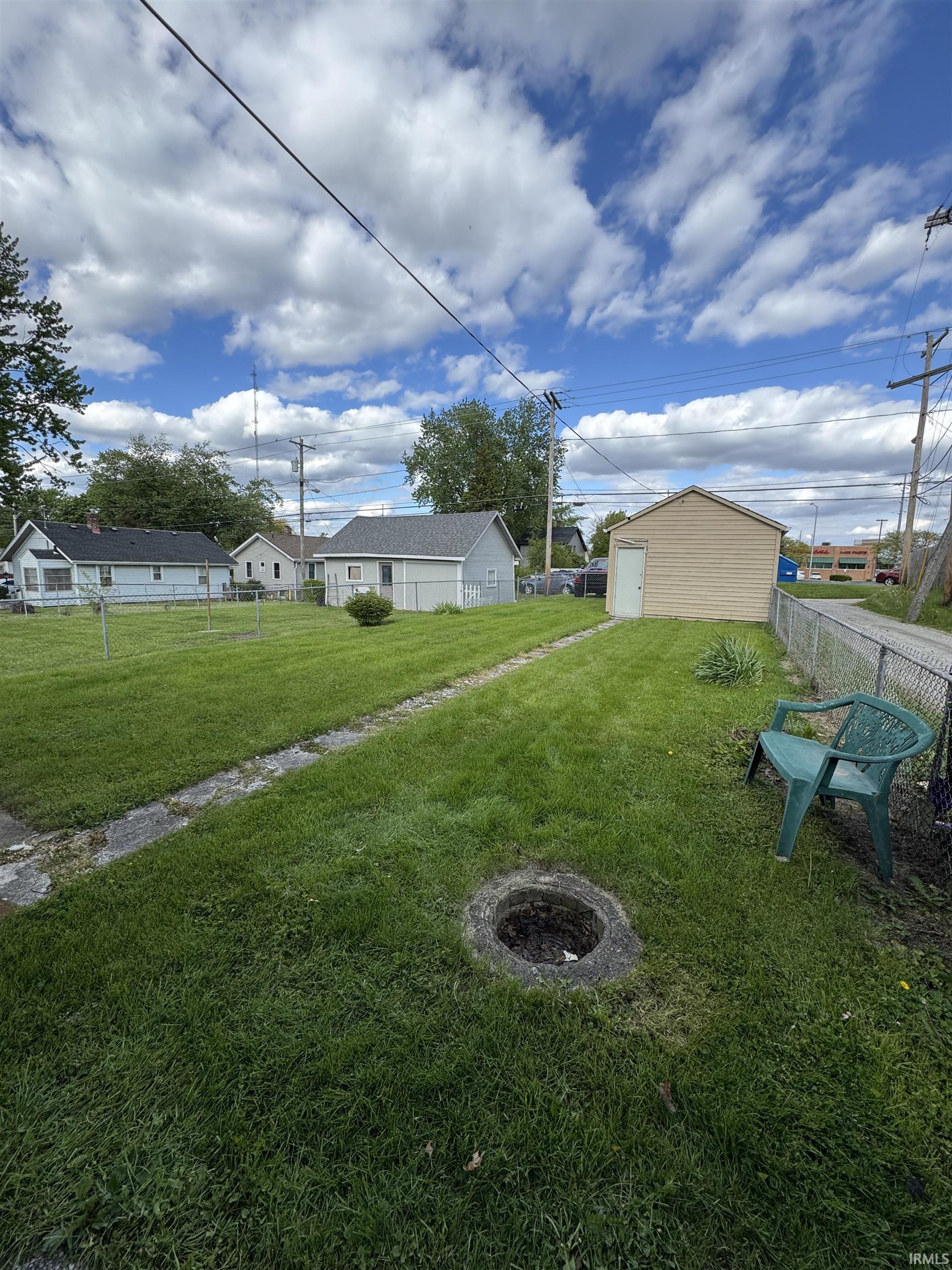 Expansive rear yard featuring green lawn, a detached garage with siding, and a chain-link fence
