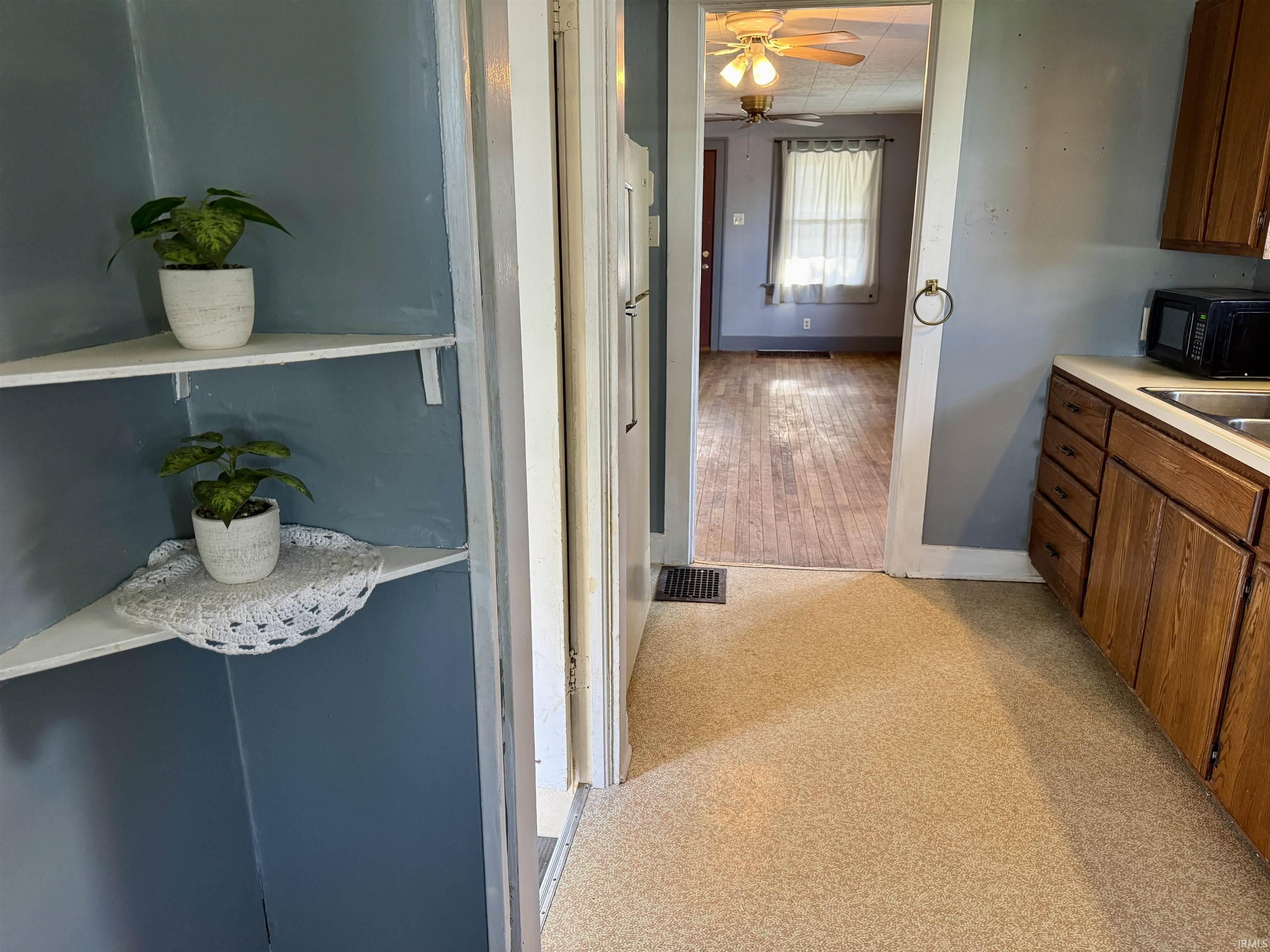Kitchen area featuring wood-finish cabinetry, a light-toned countertop, and speckled flooring