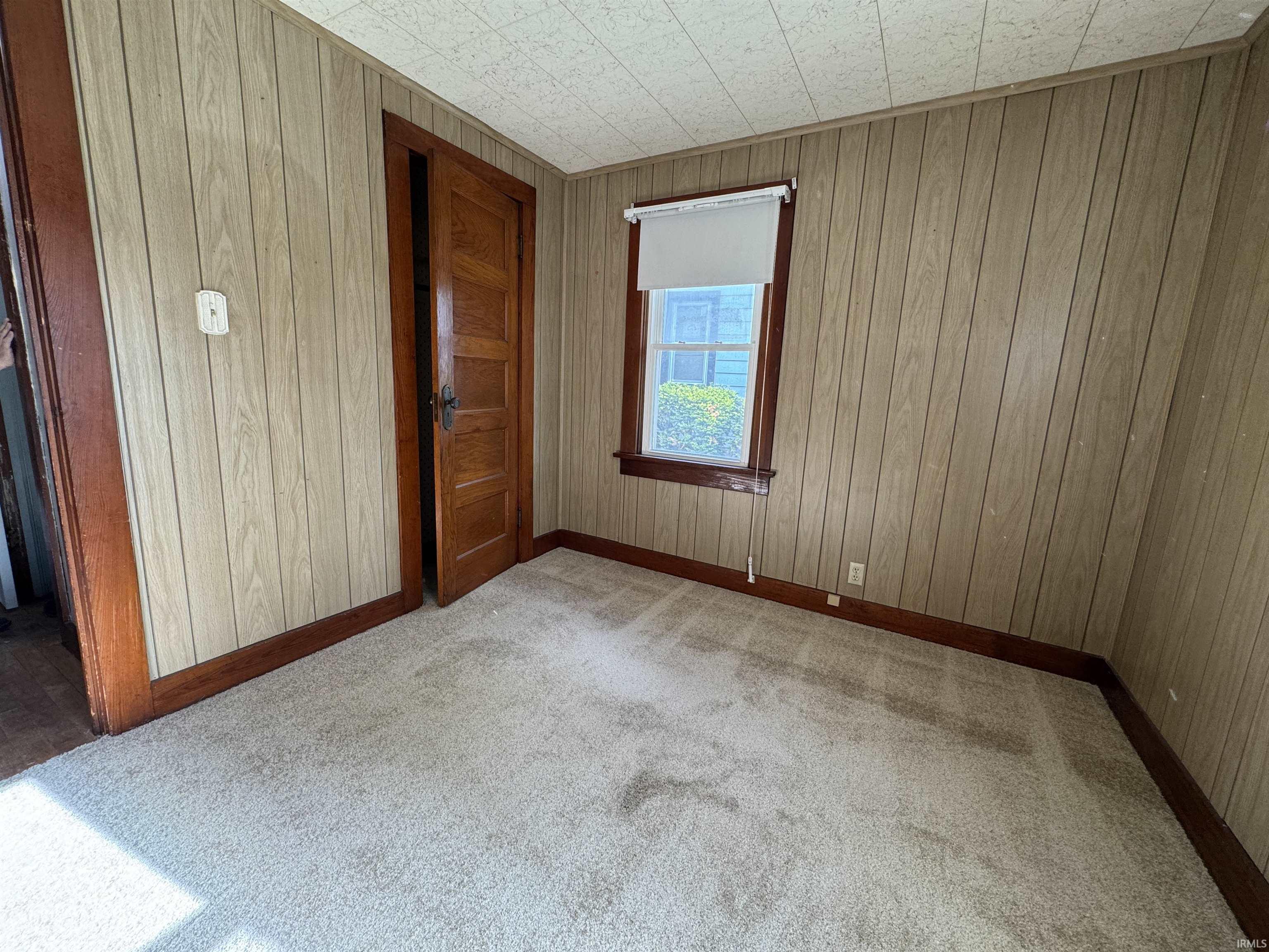 Carpeted room featuring wood-paneled walls and dark wood trim