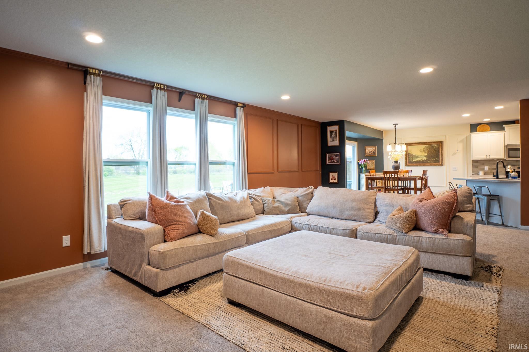 Spacious living area featuring three large windows, recessed lighting, and a neutral carpet