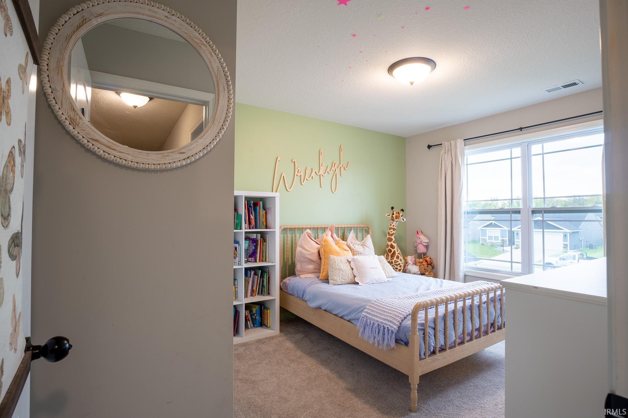 Spacious room featuring neutral carpeting, a large window with white trim, and a built-in shelf