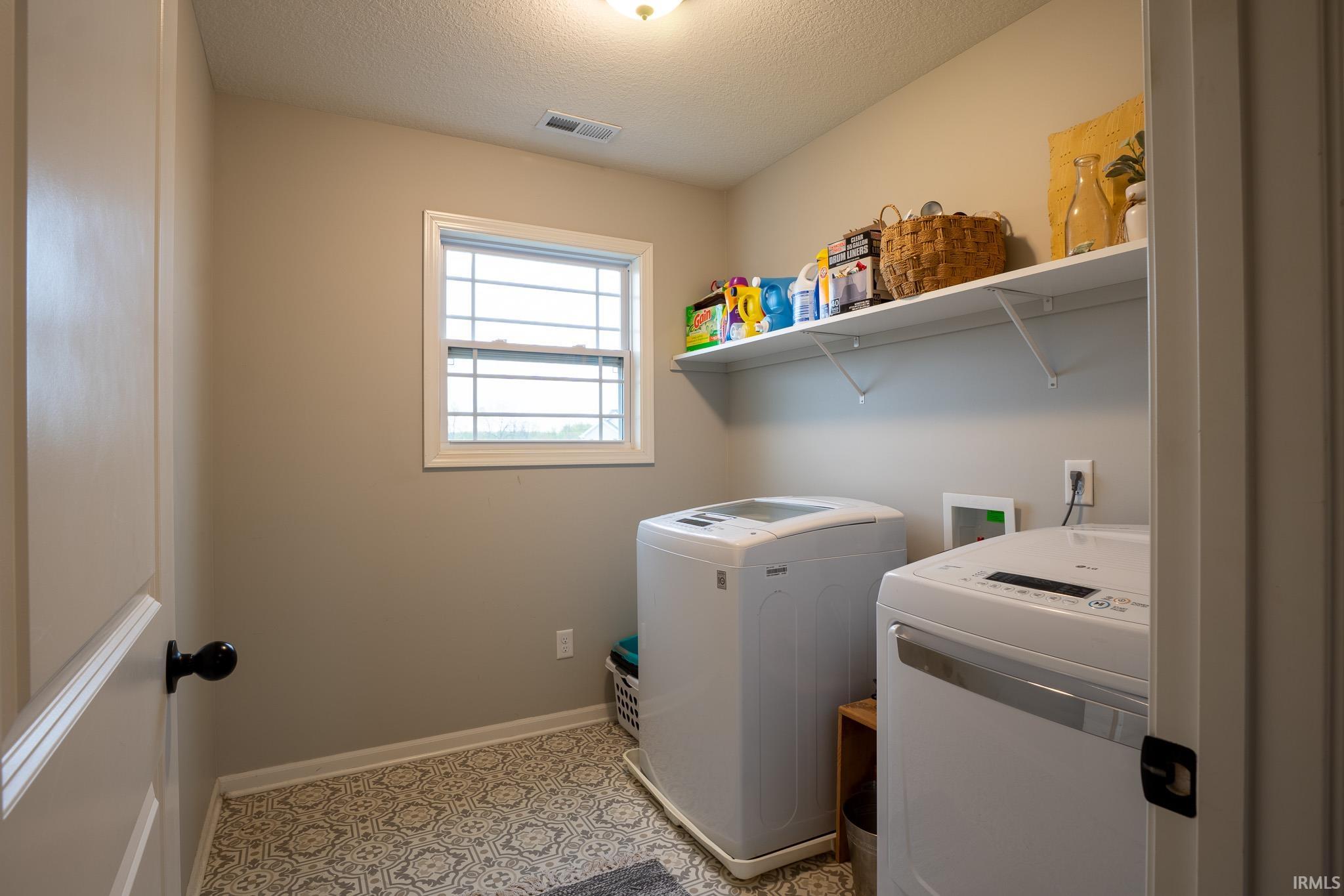 Dedicated laundry space featuring a patterned floor, a single window, and a white storage shelf