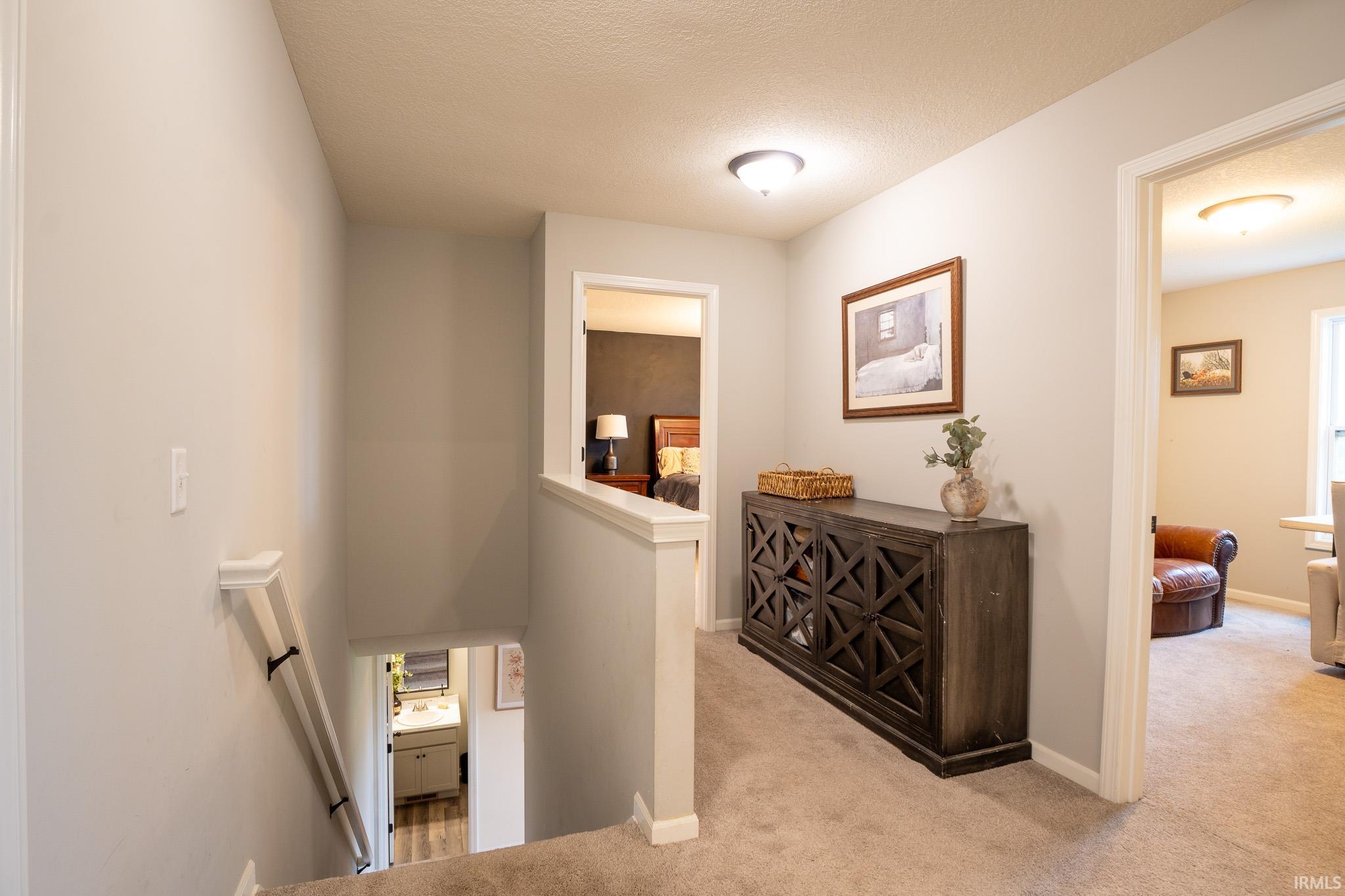 Carpeted hallway with light gray walls, white trim, and flush-mount lighting fixtures