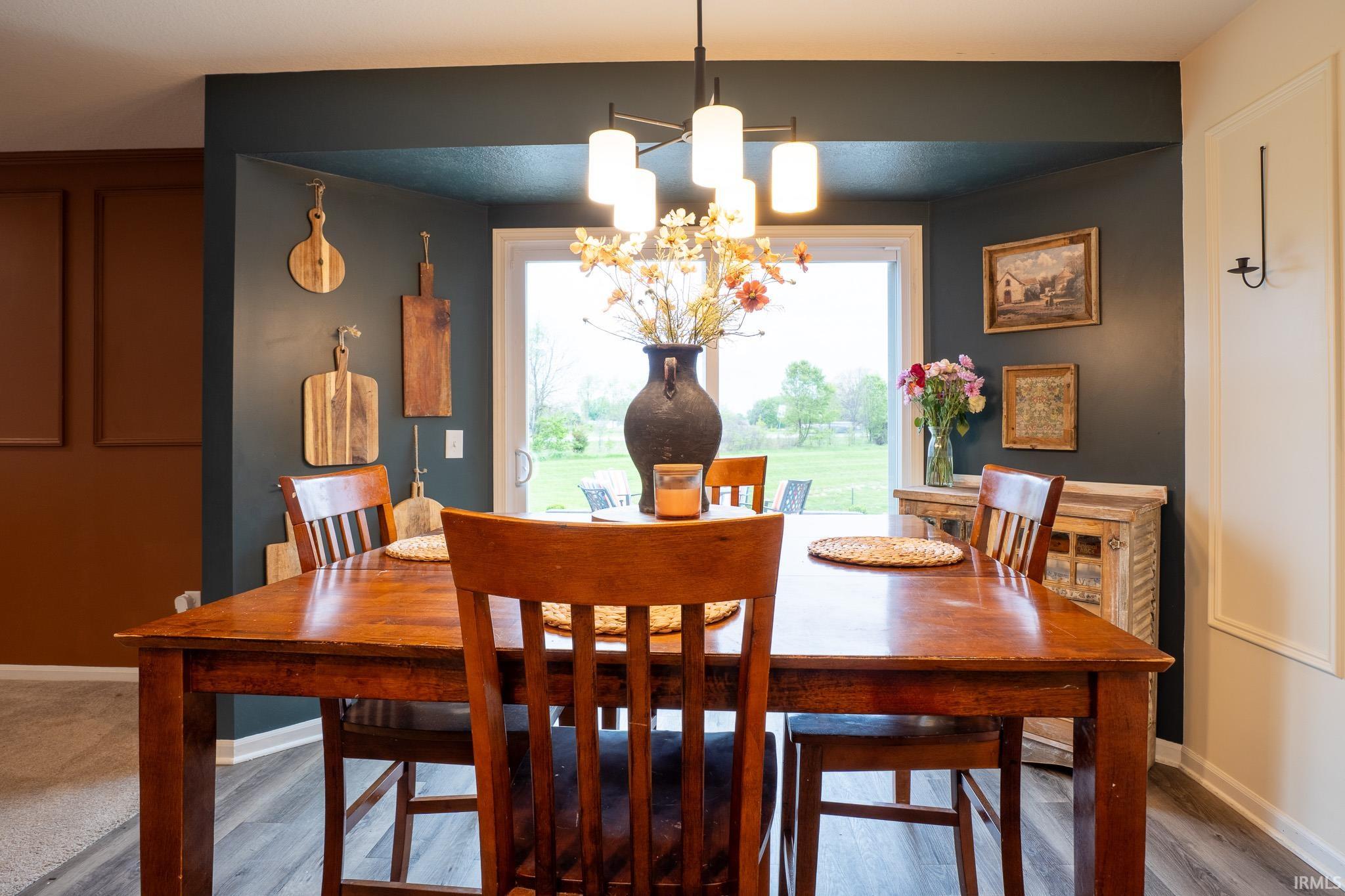 Dining area featuring wood-finish flooring, a contemporary chandelier, and a sliding glass door providing natural light