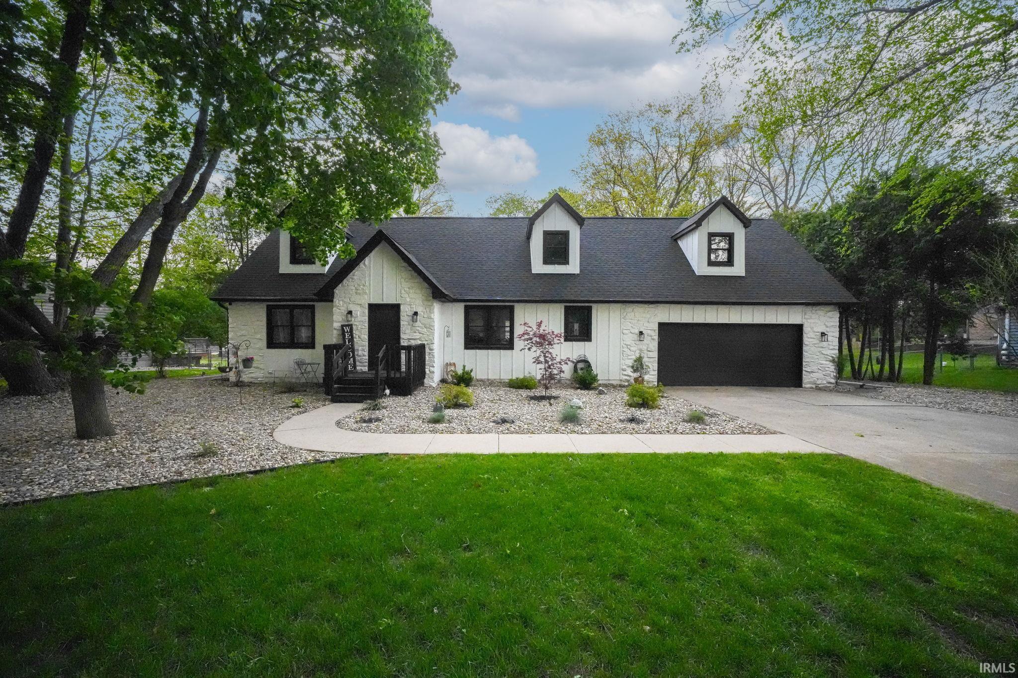 White-paneled exterior with black trim windows, a black garage door, and a dark shingled roof