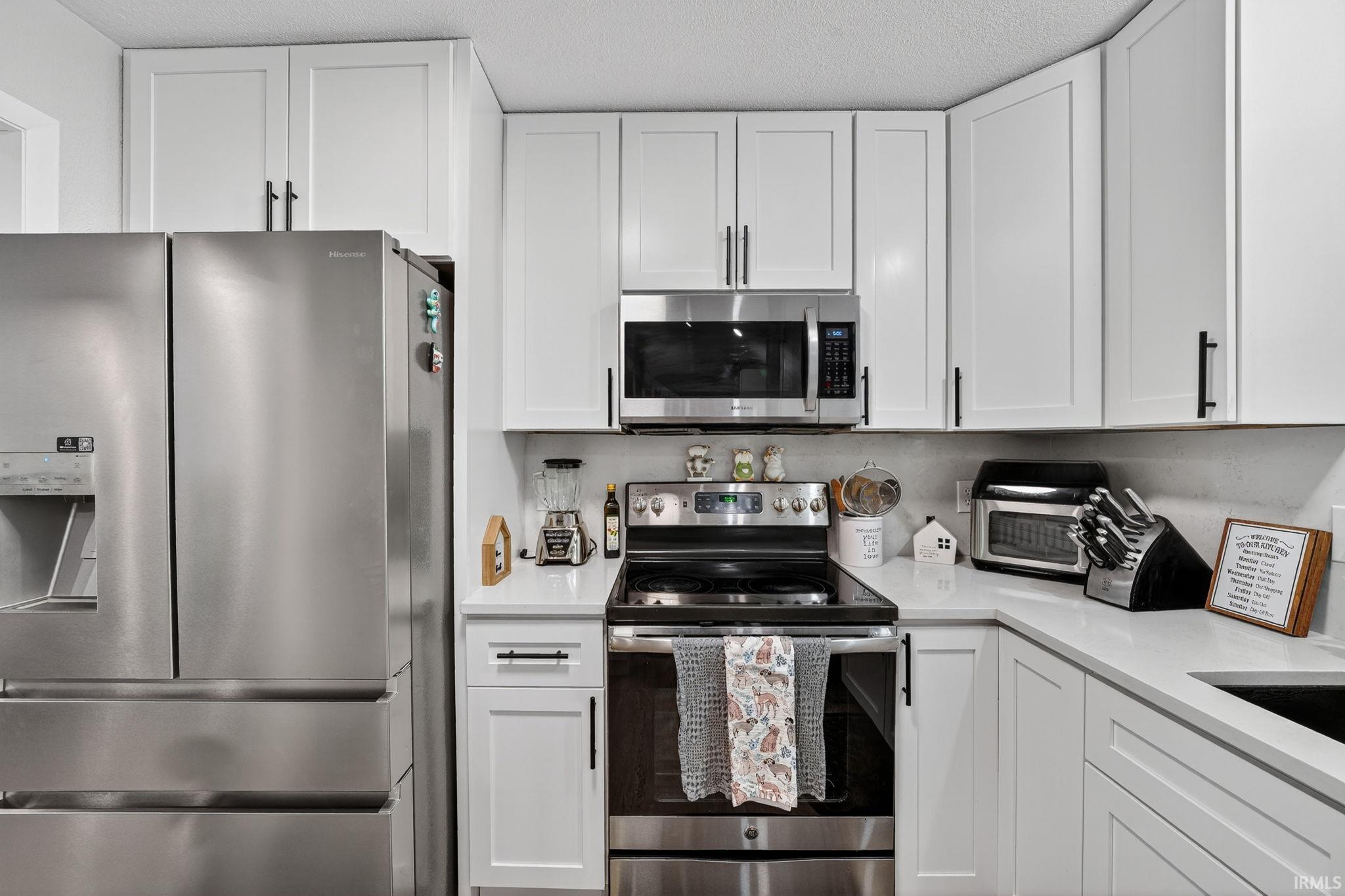 Kitchen featuring white shaker-style cabinetry, stainless steel appliances, a stainless steel range, and light-toned countertops