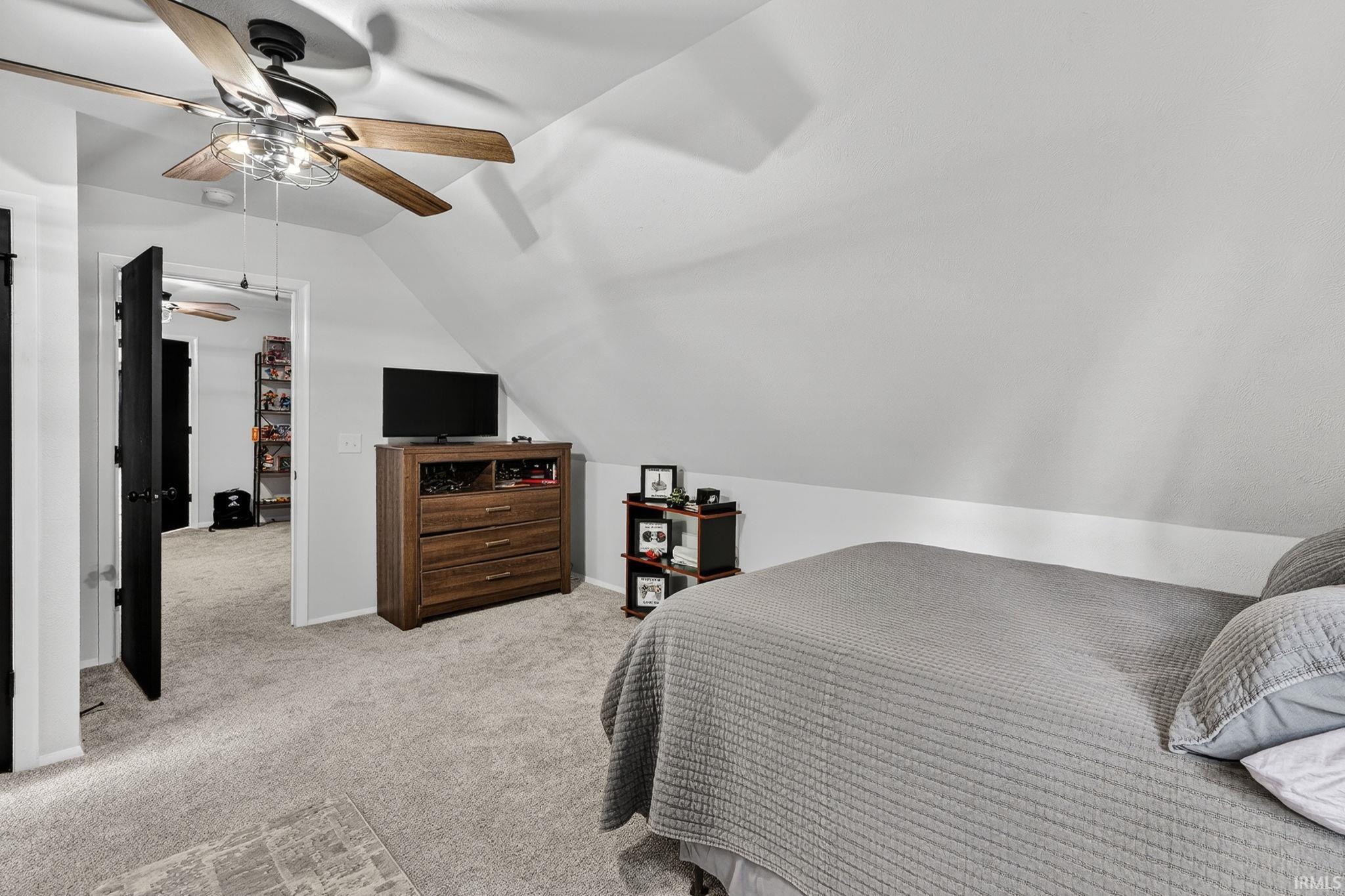 Carpeted room featuring a ceiling fan with wood-finish blades and a decorative light fixture