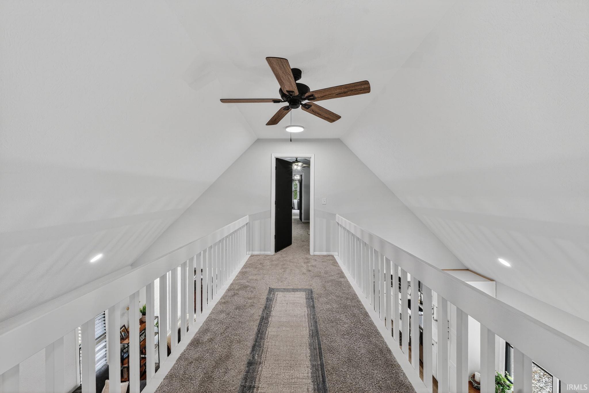 Carpeted hallway with white railings and a paddle ceiling fan