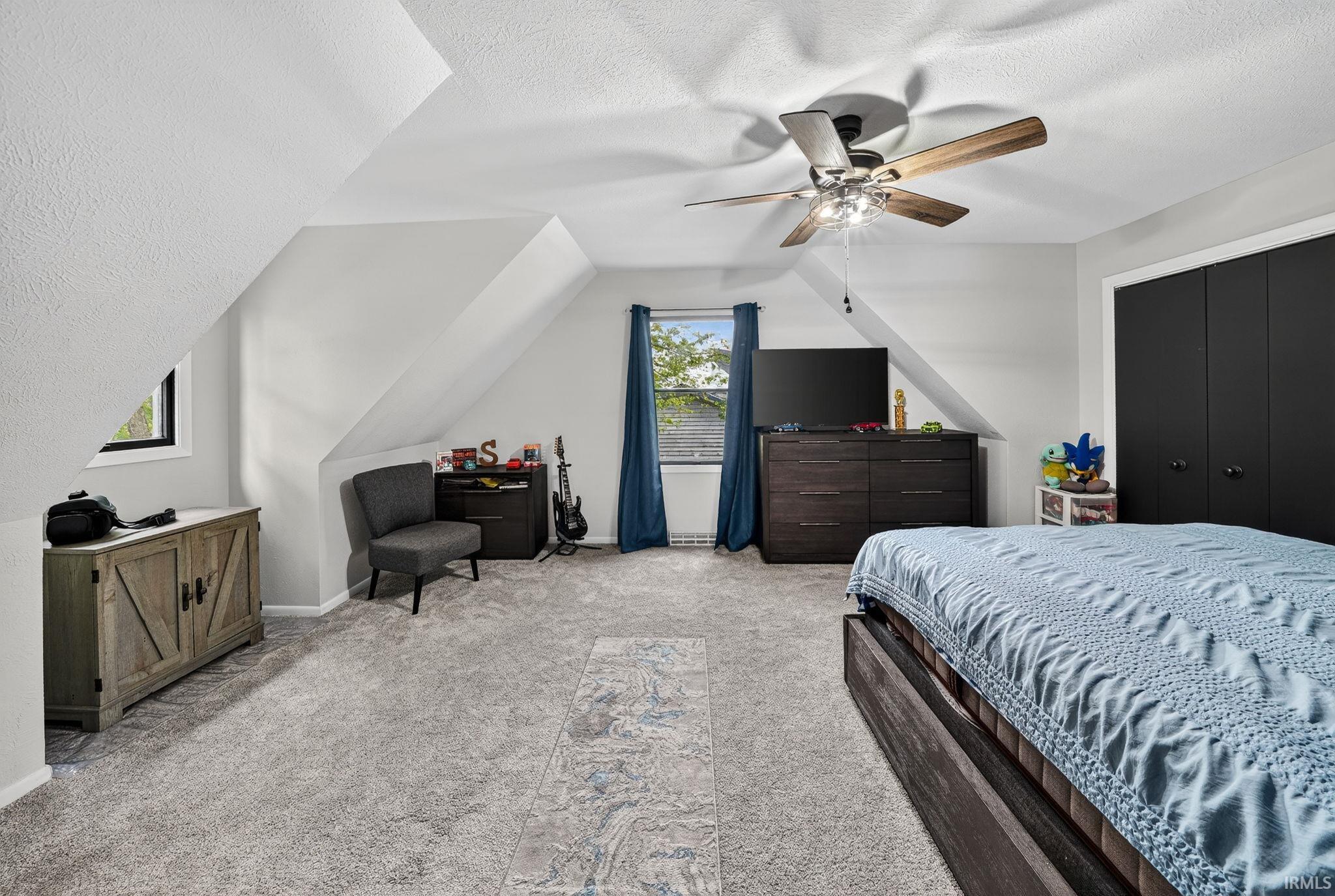 Attic room featuring sloped ceilings, light gray carpet, and a ceiling fan with integrated lighting