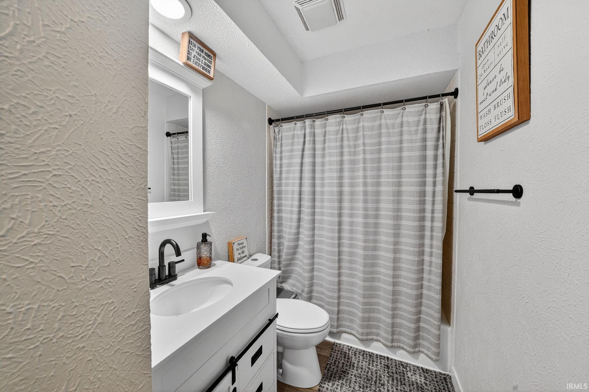 Bathroom featuring a white vanity with integrated sink, black hardware, and wood-finish flooring