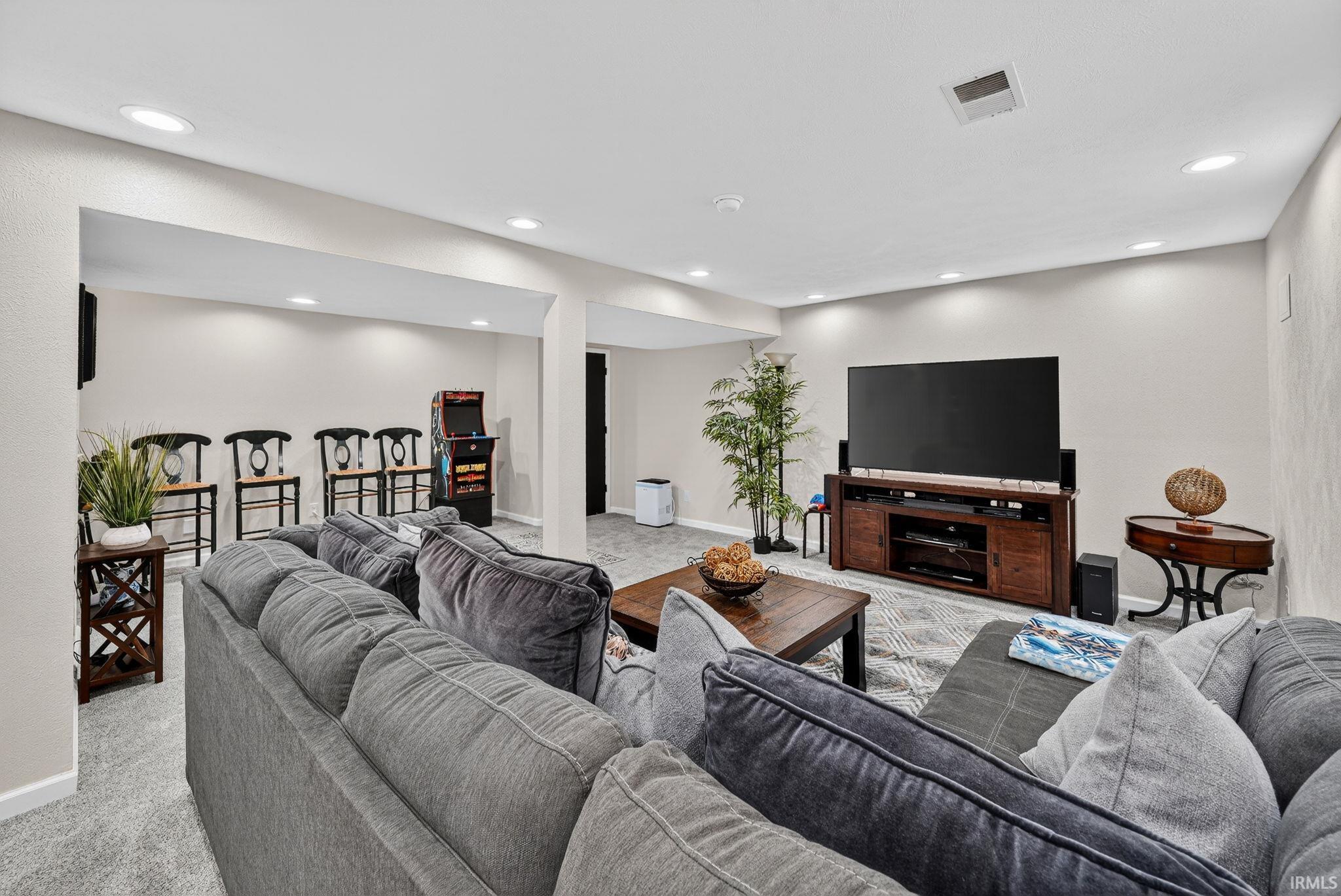 Recessed lighting illuminates this carpeted lower level, featuring a dedicated media area with a built-in media console