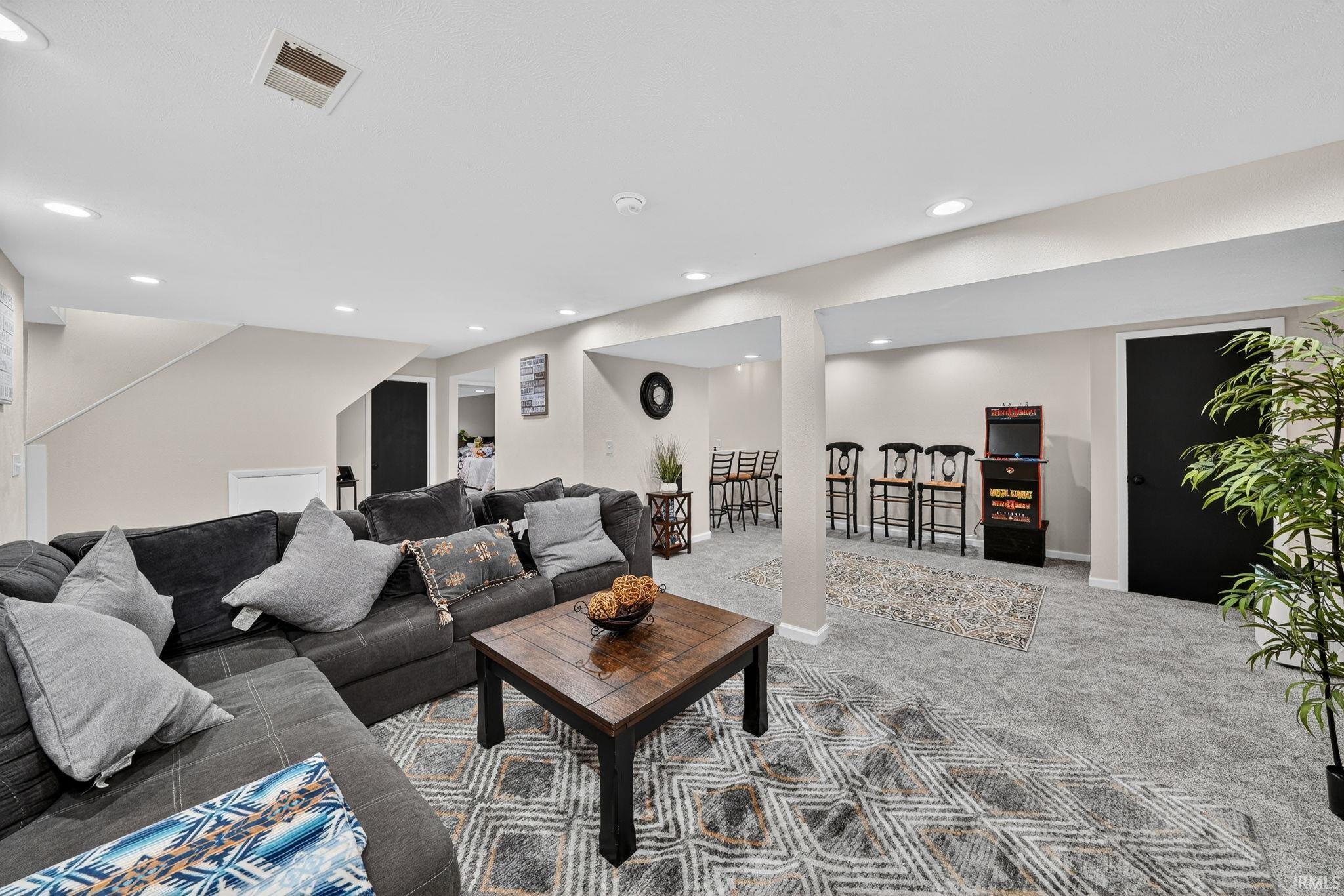 Spacious finished room featuring light gray walls, recessed lighting, and patterned carpeting