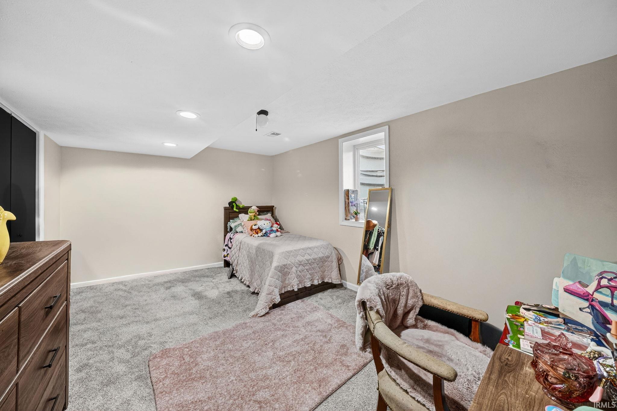Recessed lighting illuminating a spacious room with light gray wall paint and gray carpeting