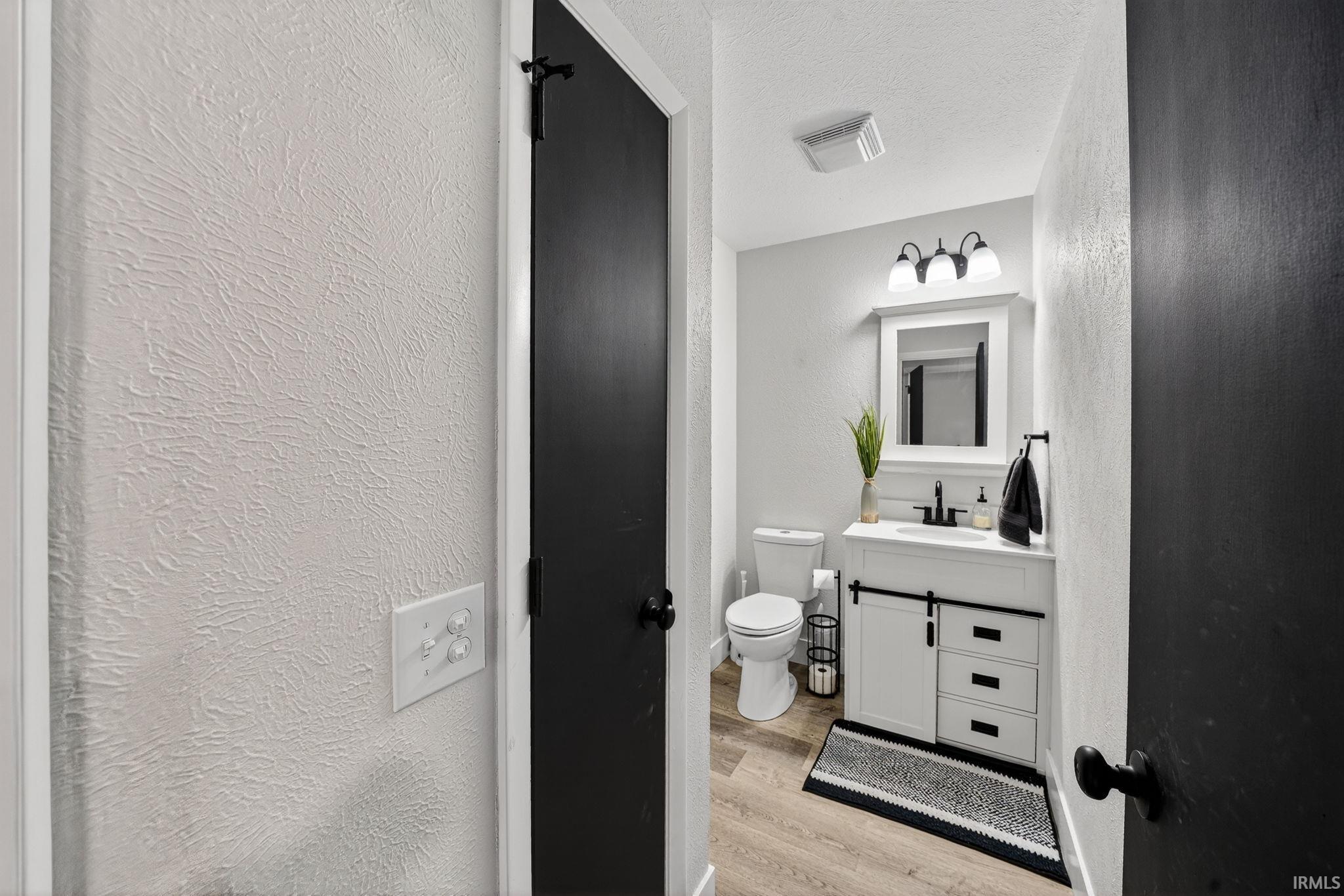 Bathroom featuring a white vanity with black hardware, coordinating black faucet, and a three-light fixture above a framed mirror