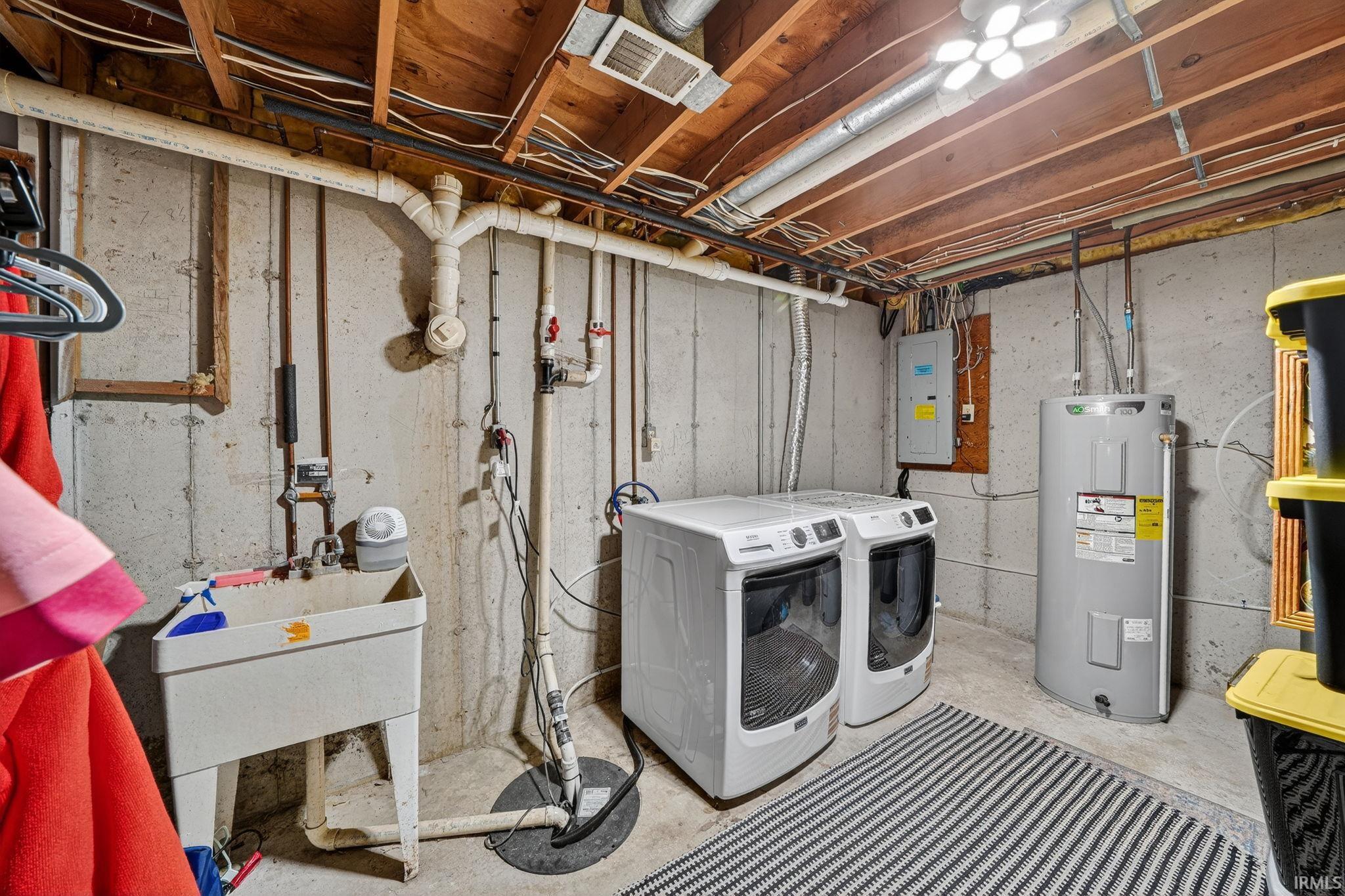 Utility area featuring exposed wood joists, concrete walls, a large utility sink, a sump pump, and a water heater