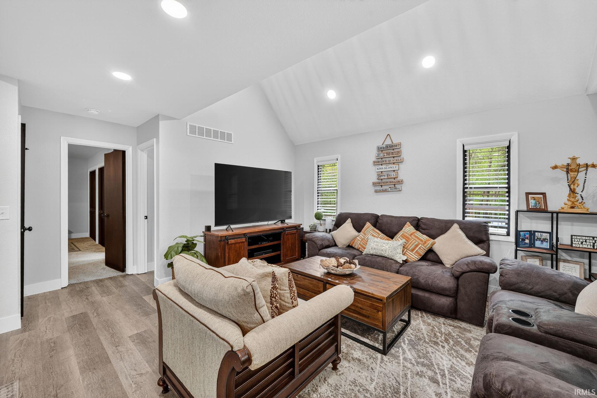 Vaulted ceiling living area featuring recessed lighting and wood-finish flooring