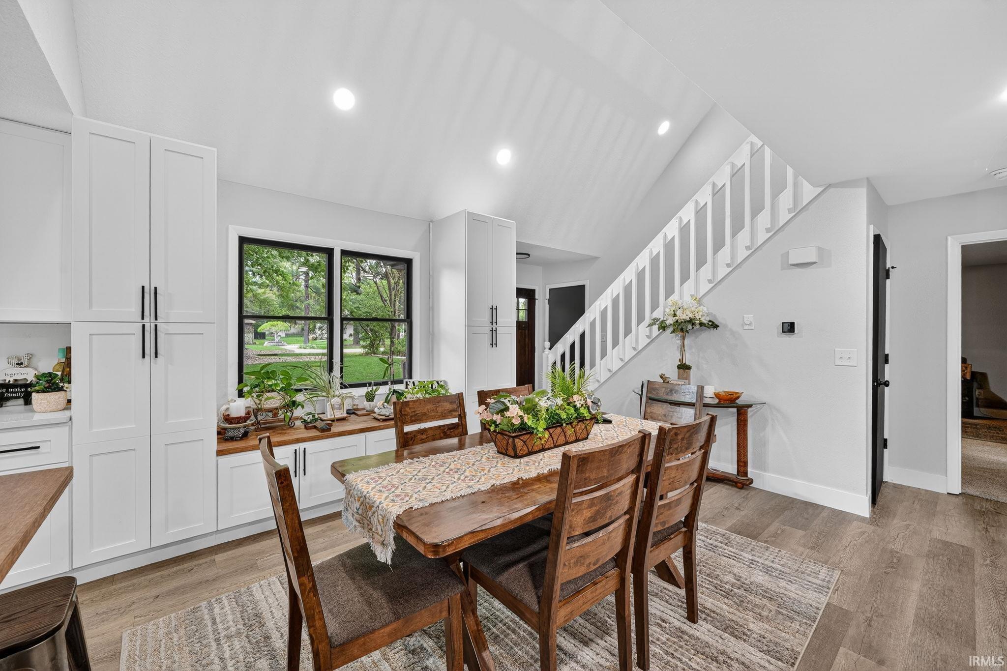 Dining area featuring wood-finish flooring and a white painted staircase with open balusters