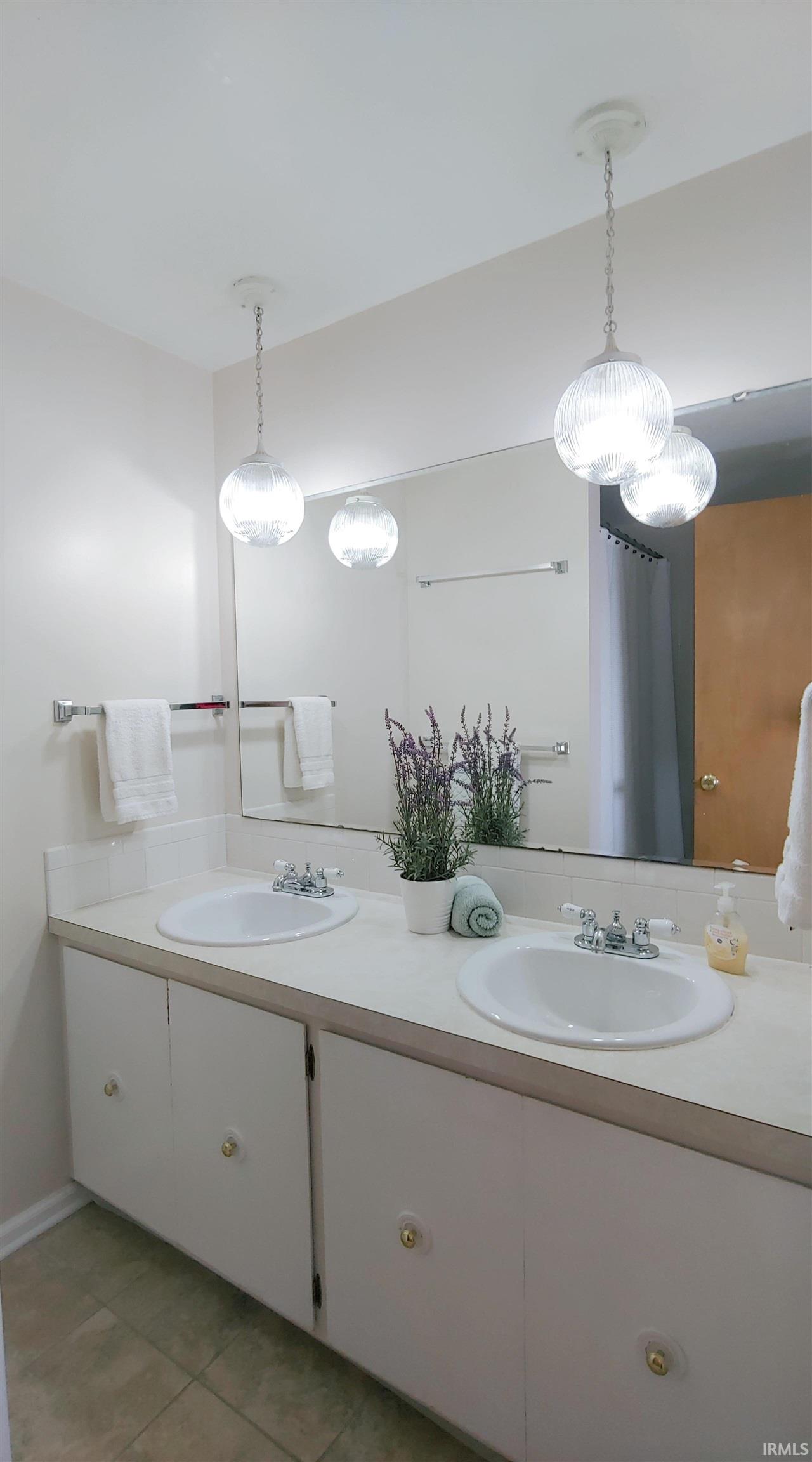 Dual vanity sinks, white cabinetry, and chrome faucets.