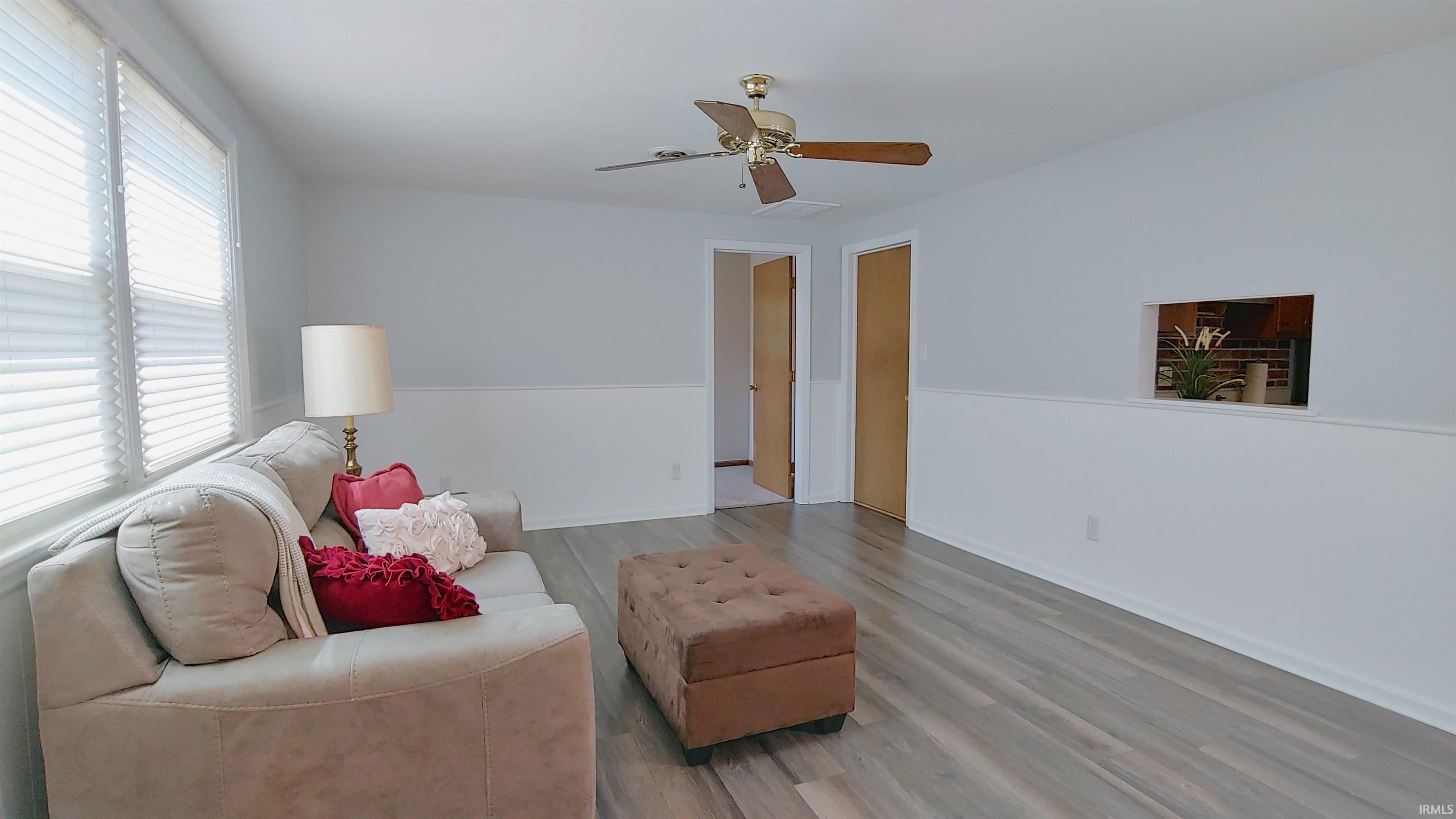 Spacious living area featuring vinyl plank flooring, a ceiling fan, and window blinds.
