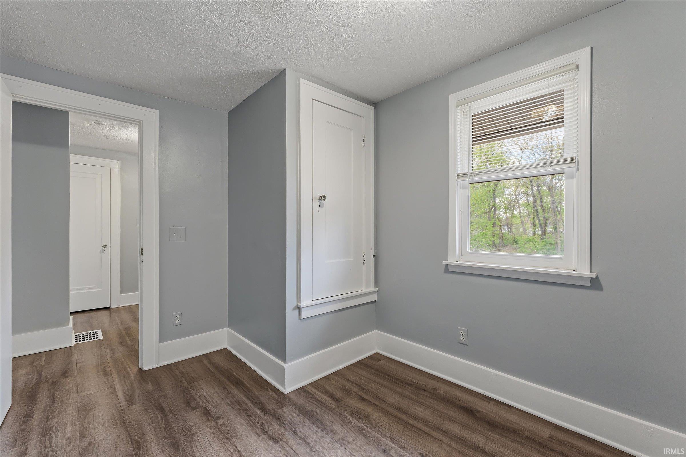 Interior room featuring wood-finish flooring, light grey walls, and white trim