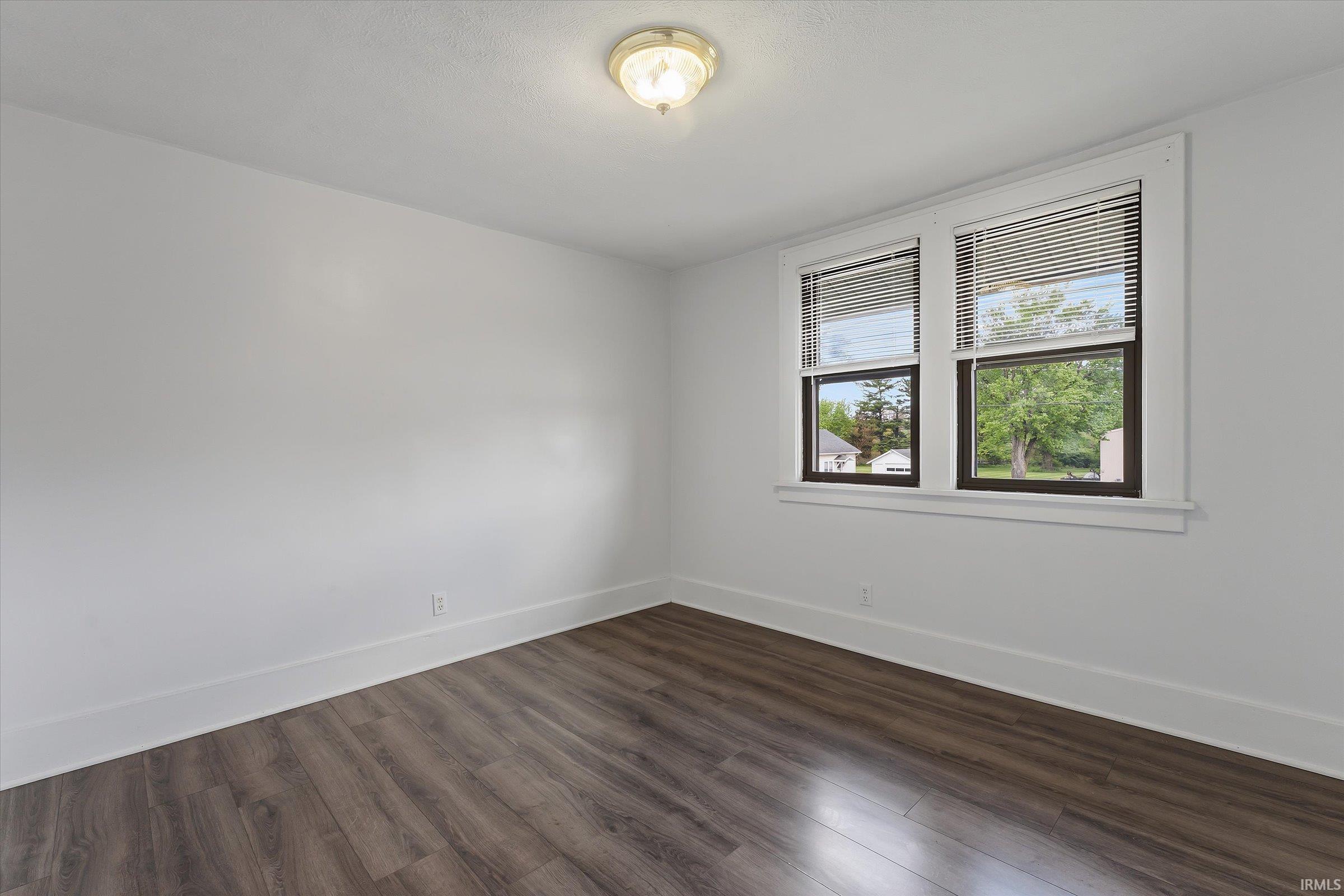 Bright interior space featuring wood-finish flooring, white baseboards, and neutral wall paint