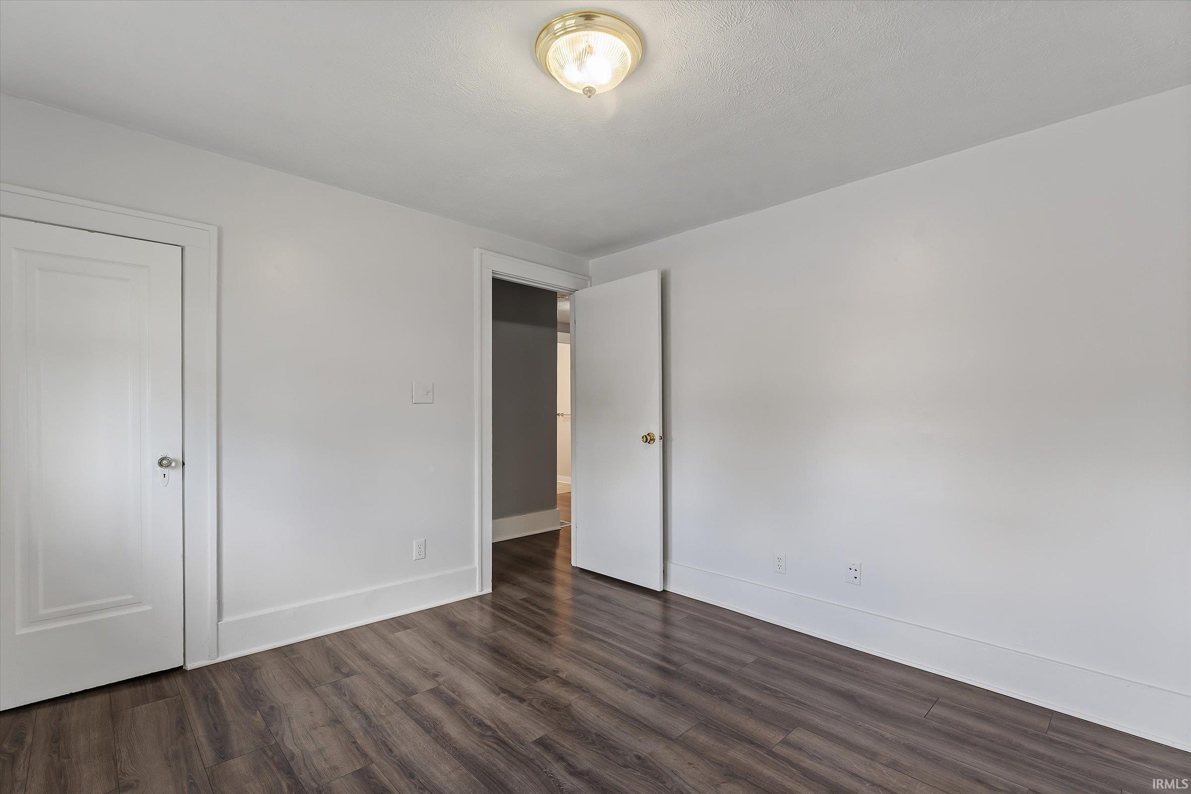 Room with wood-finish flooring and white walls, featuring a flush-mount ceiling light