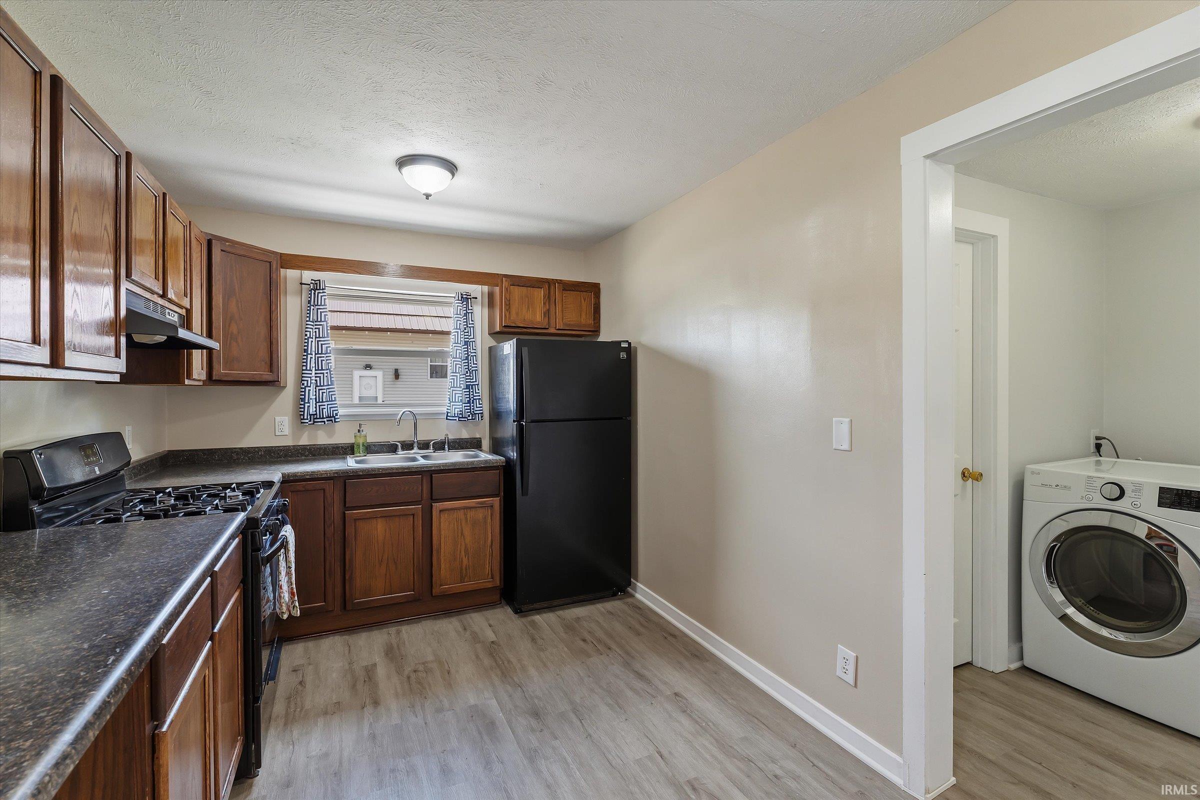 Kitchen featuring wood-finish cabinetry, dark countertops, and a full suite of black appliances