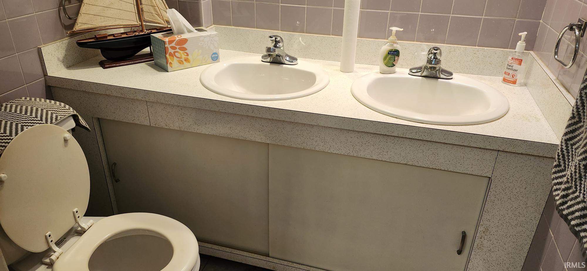 Dual vanity with integrated sinks, speckled countertop, and white cabinetry