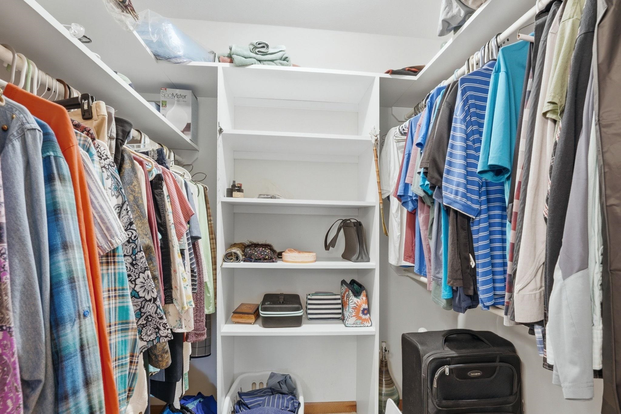 Walk-in closet with built-in shelving, multiple hanging rods, and wood-finish flooring
