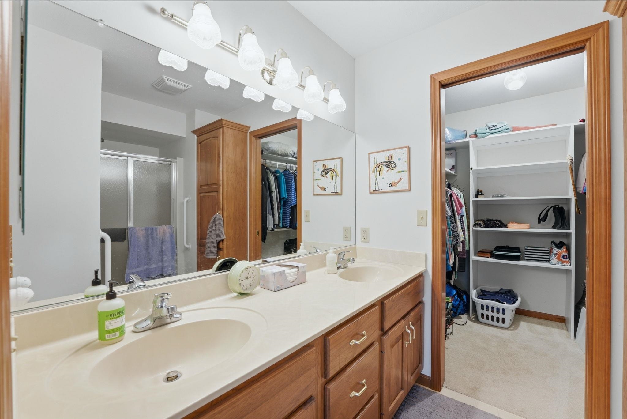 Bathroom vanity featuring dual integrated sinks, an expansive mirror, and a multi-bulb light fixture