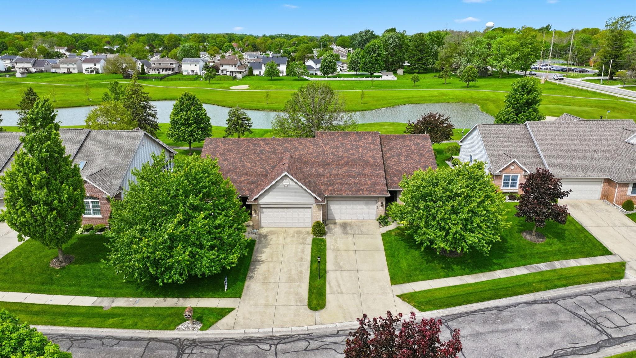 Residential property featuring a dual-car garage, mature landscaping, and a manicured lawn