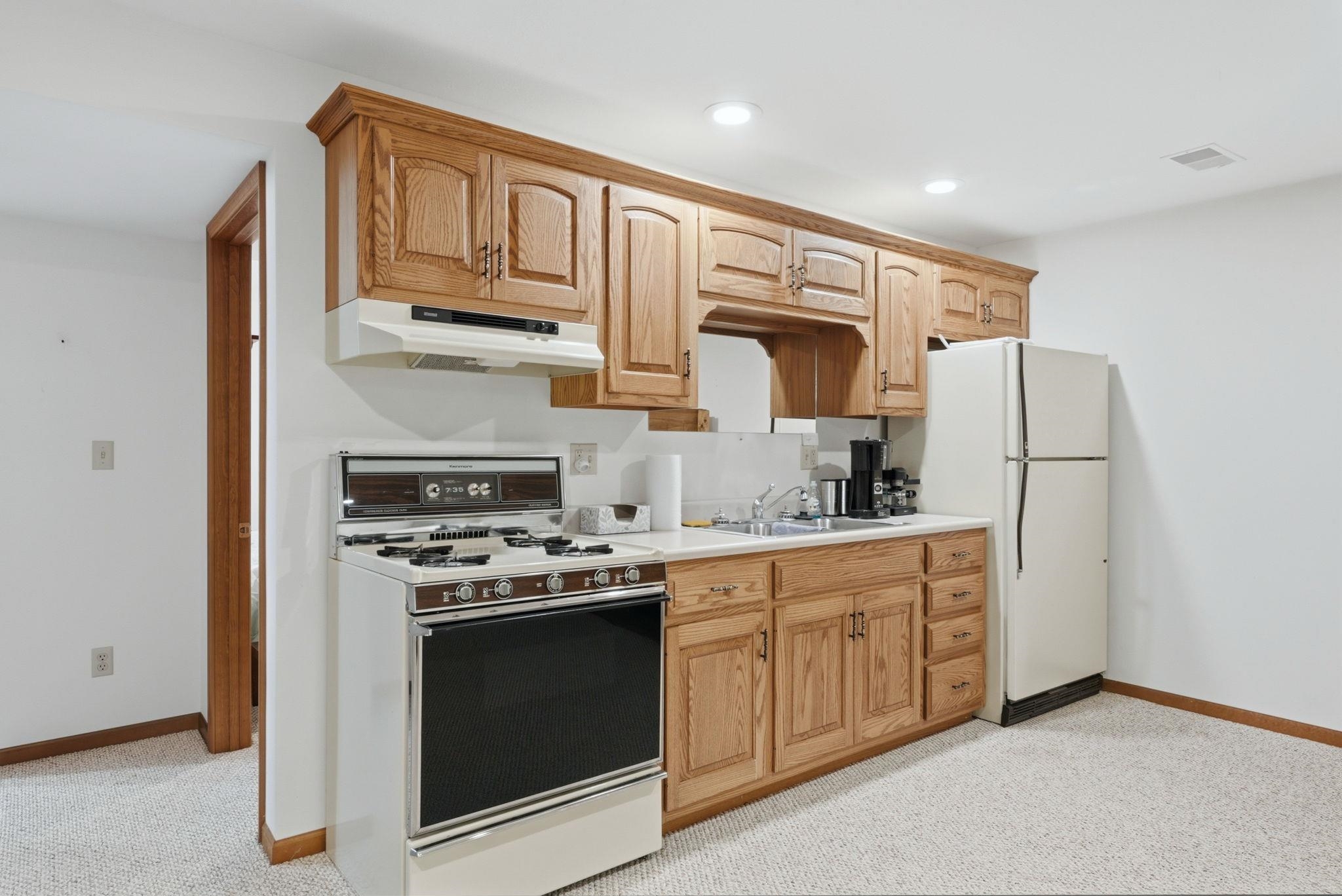 Kitchenette featuring wood cabinetry, white countertops, a four-burner range with oven, a refrigerator, and recessed ceiling lighting