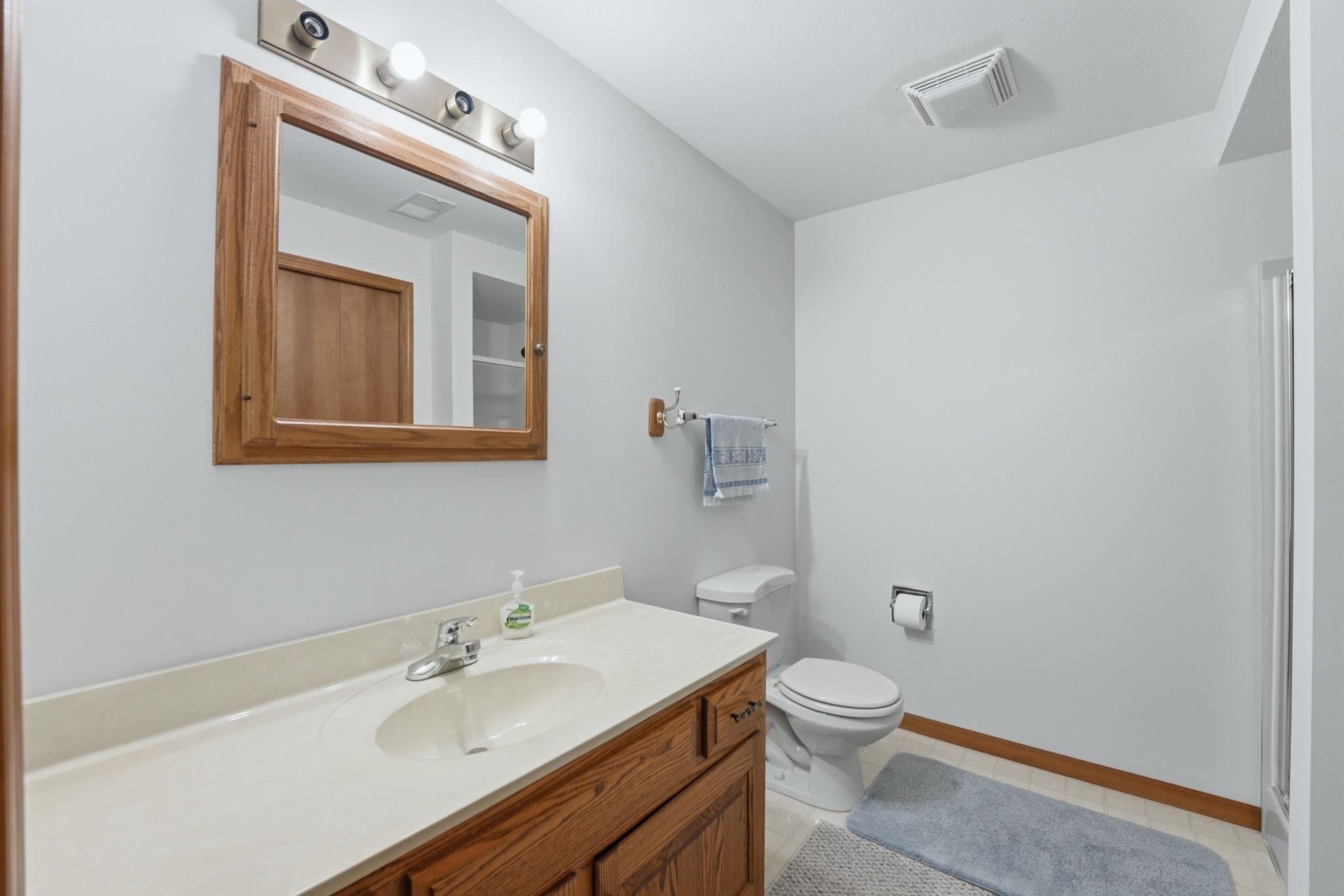 Bathroom featuring a wood-finish vanity with an integrated sink and light-colored countertop