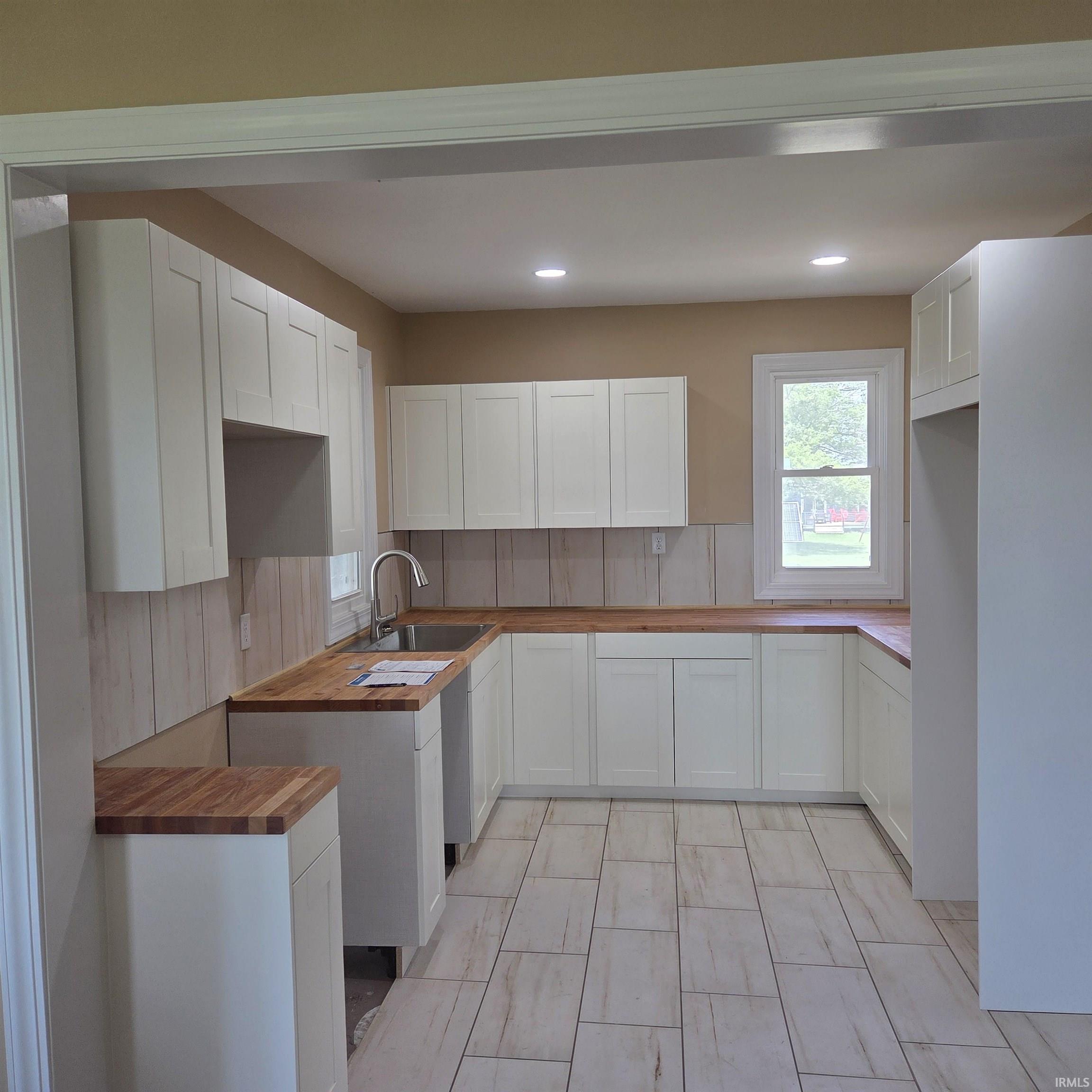 U-shaped kitchen featuring white shaker cabinetry and wood-finish countertops