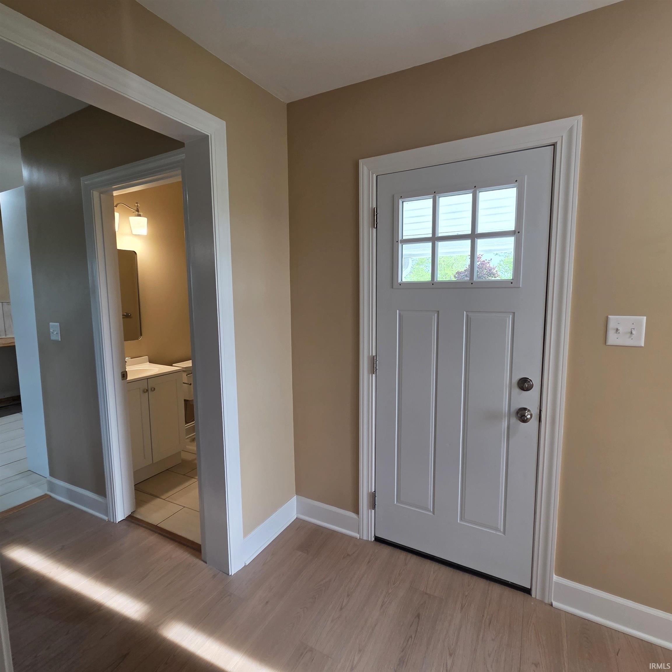Entry area featuring light wood-finish flooring, neutral wall tones, and white trim